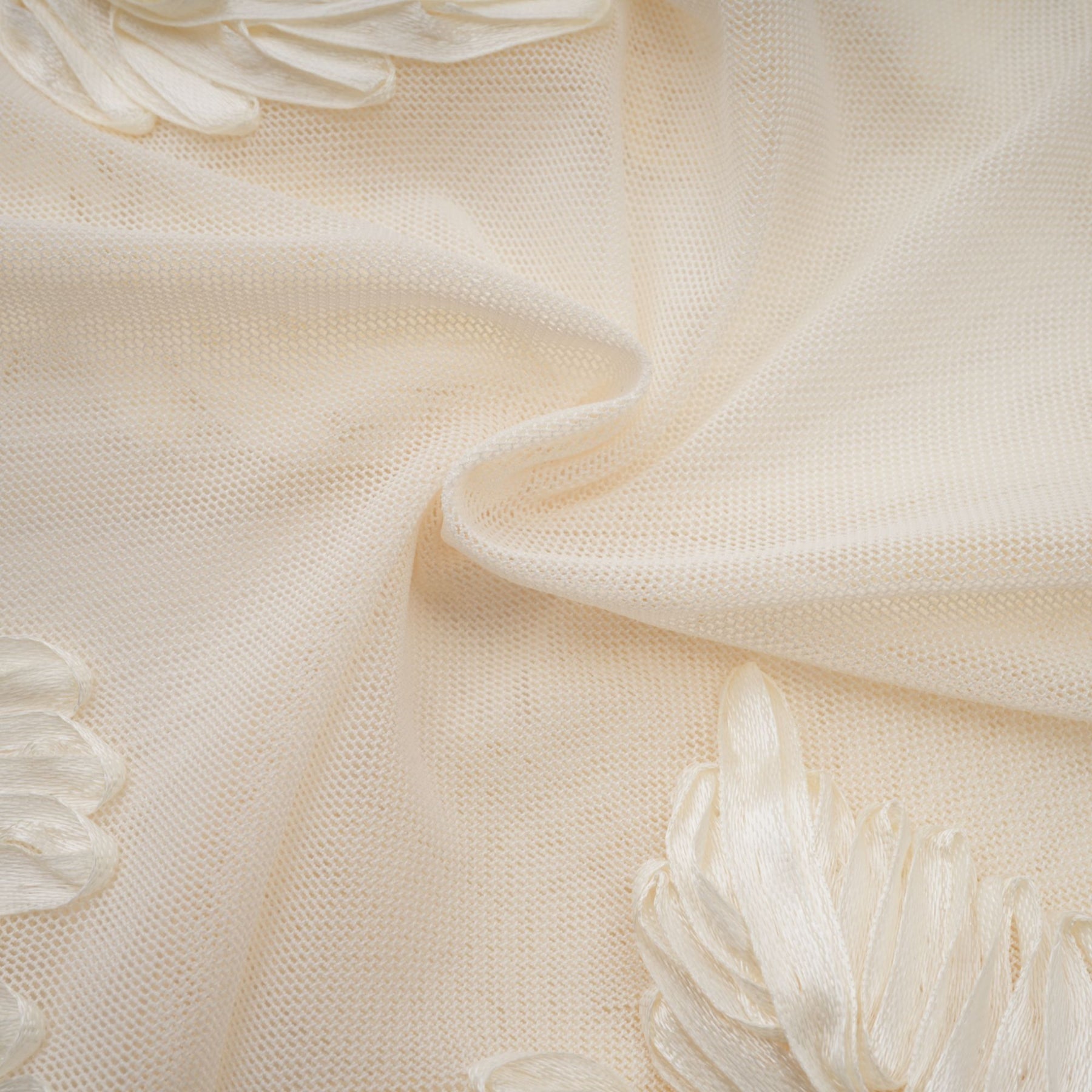 A woman wearing a long offshoulder maxi dress in neutral tones featuring embroidered details