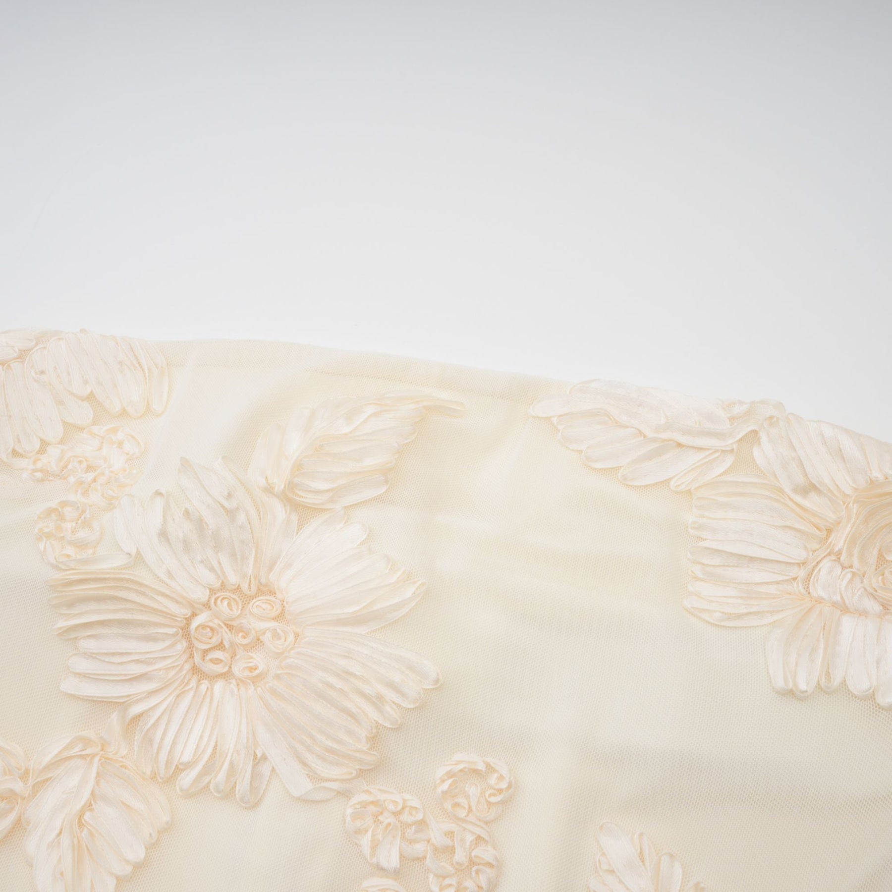 A woman wearing a long offshoulder maxi dress in neutral tones with embroidered details standing in a relaxed pose