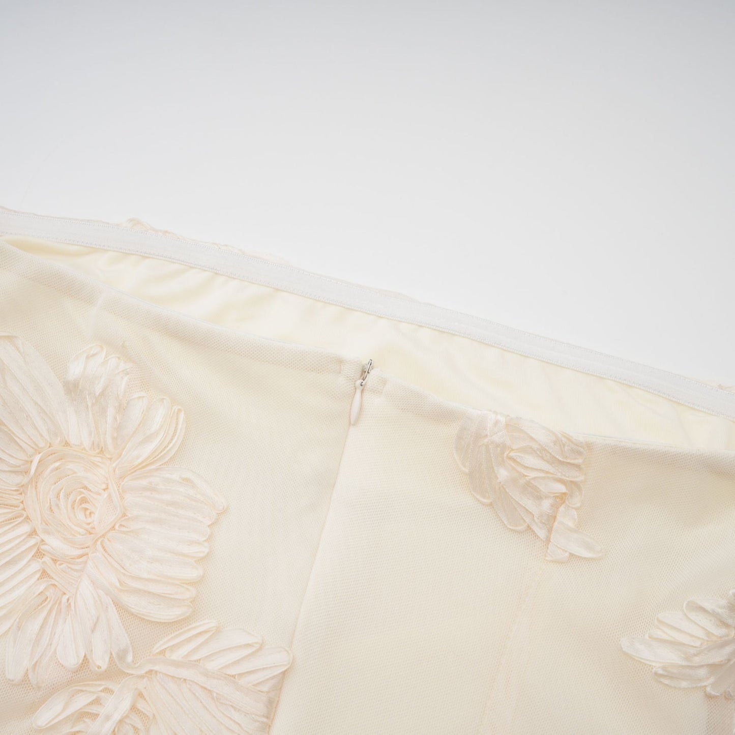 A woman wearing a long offshoulder maxi dress in neutral tones with embroidered details standing in a relaxed pose