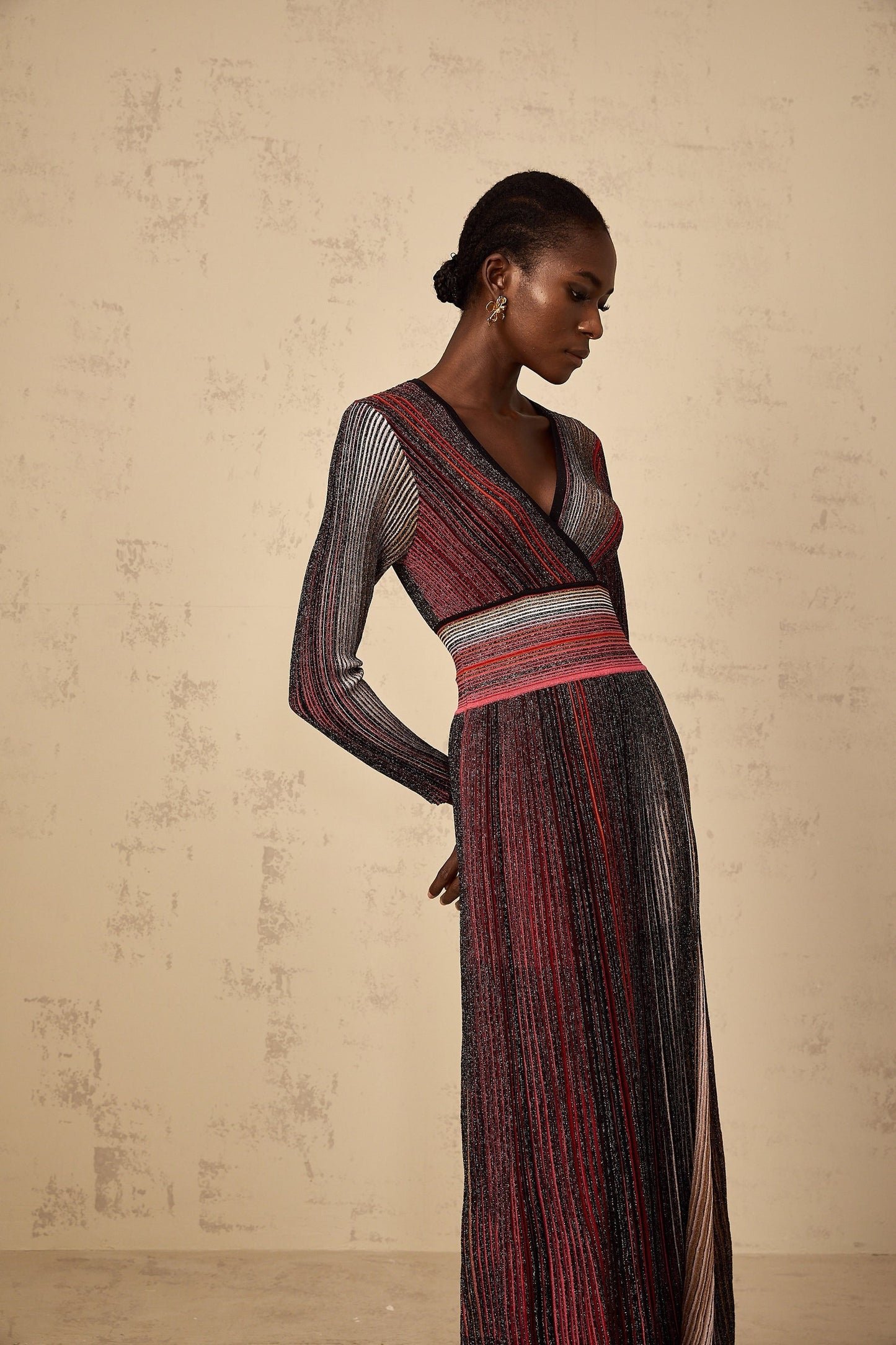 A woman wearing a long red maxi dress with long sleeves featuring sequin stripes on the knit fabric
