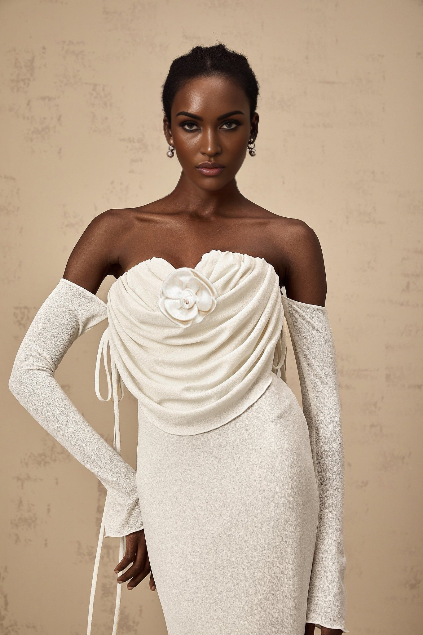 A woman wearing a long strapless maxi dress with a floral pattern The dress is ruched and features floral applique details It has a fitted bodice and flows out into a full skirt