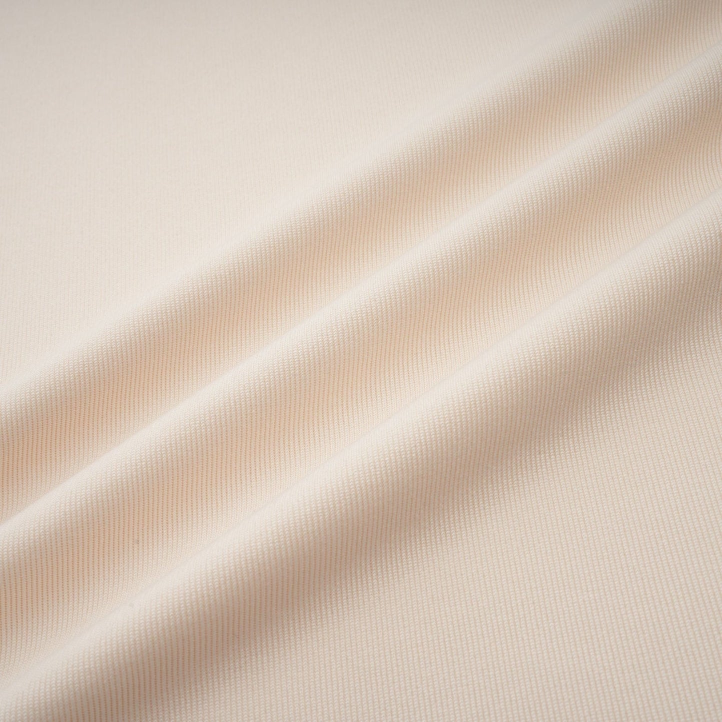 A woman wearing a long white maxi dress with a deep V neckline and draped fabric details standing in a relaxed pose