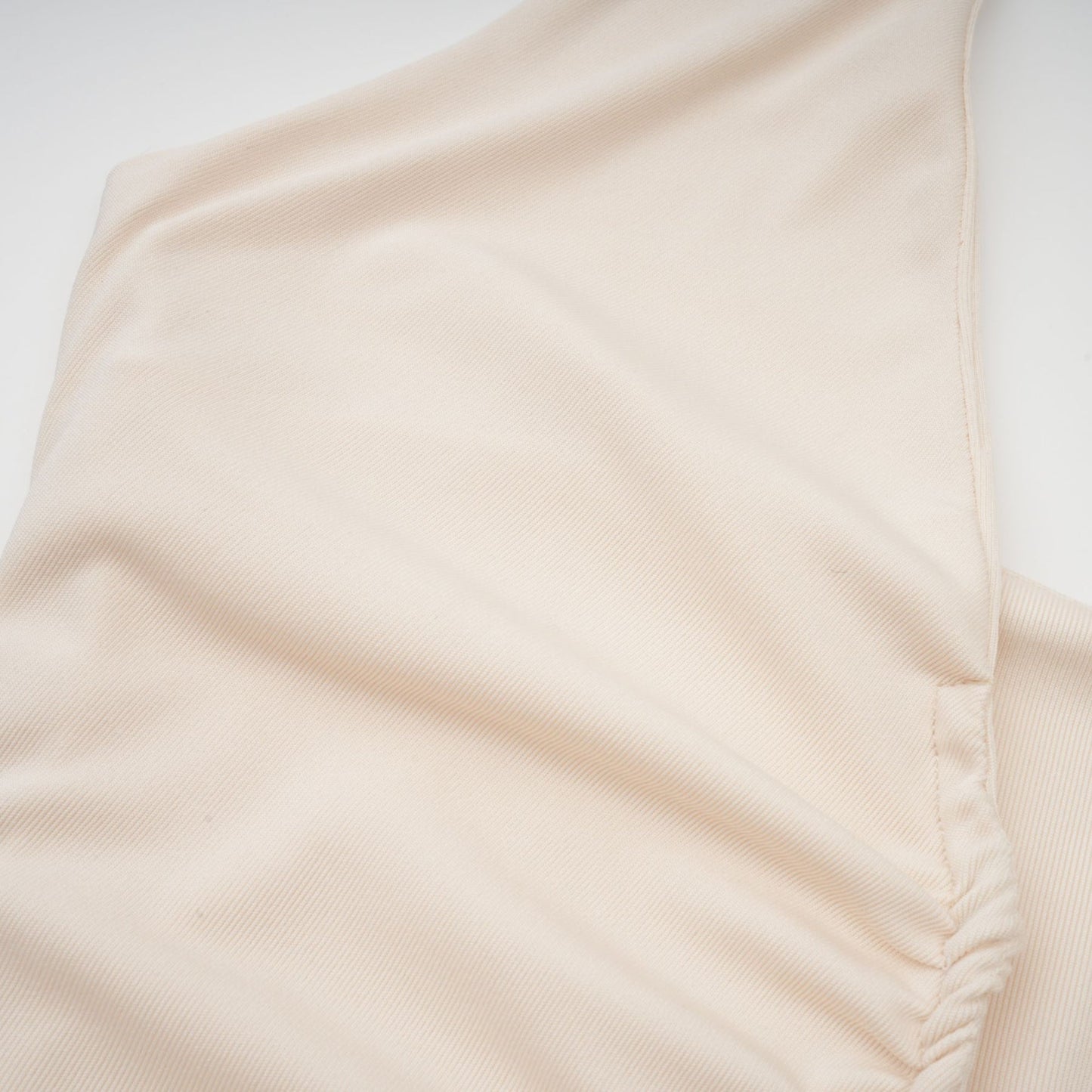 A woman wearing a long white maxi dress with a plunging V neckline and draped fabric detail