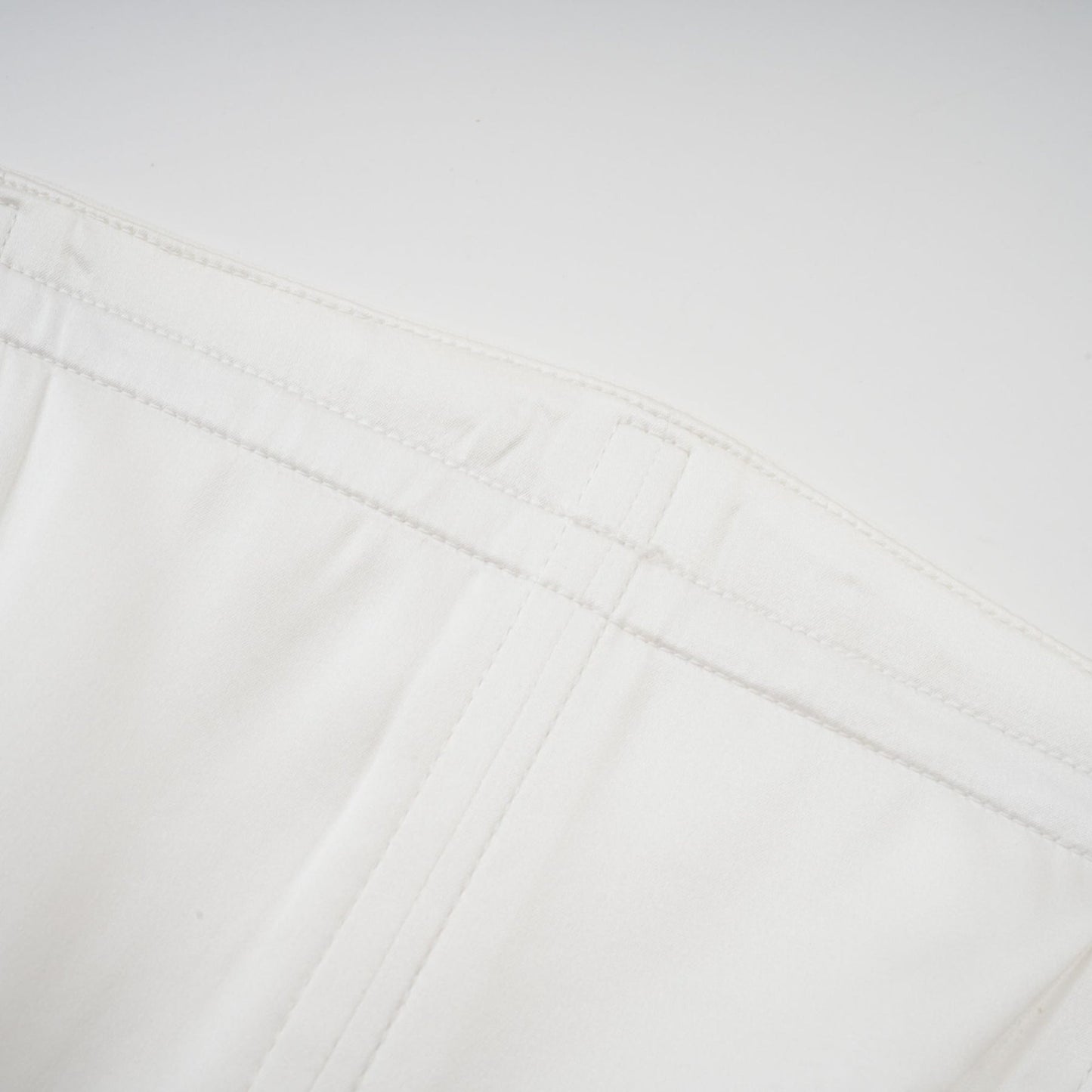 A woman wearing a long white pleated maxi dress with an offshoulder neckline