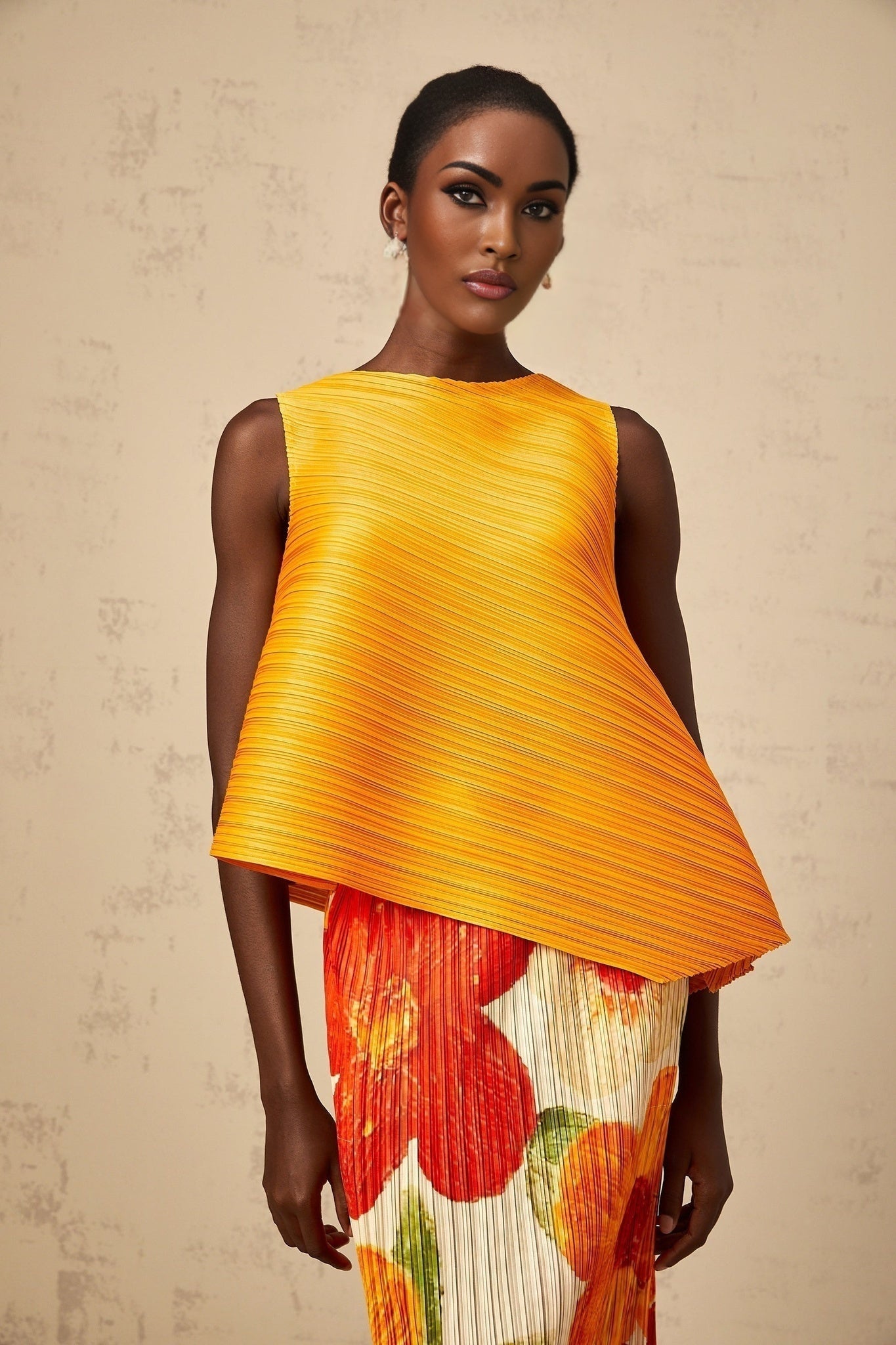 A woman wearing a matching amberorange set consisting of a crinkled texture top and skirt The outfit has a vibrant warm color and textured finish