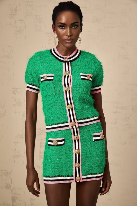 A woman wearing a matching green knitted top and skirt set The top is sleeveless with a scoop neck The skirt is knee length and form fitting The outfit is styled on a model against a plain background