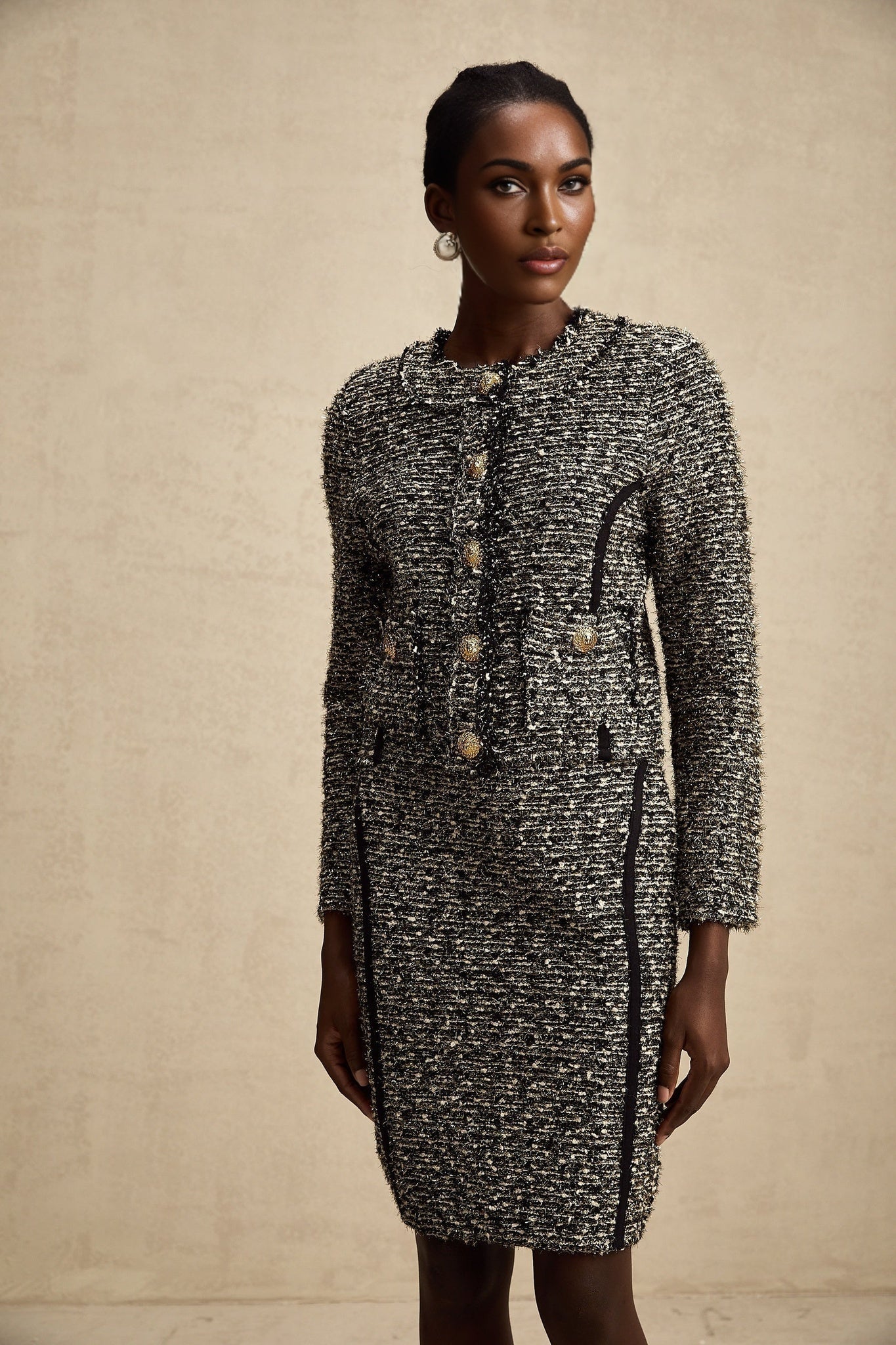 A woman wearing a matching jacket and skirt set in contrasting colors with shimmering lurex fabric details