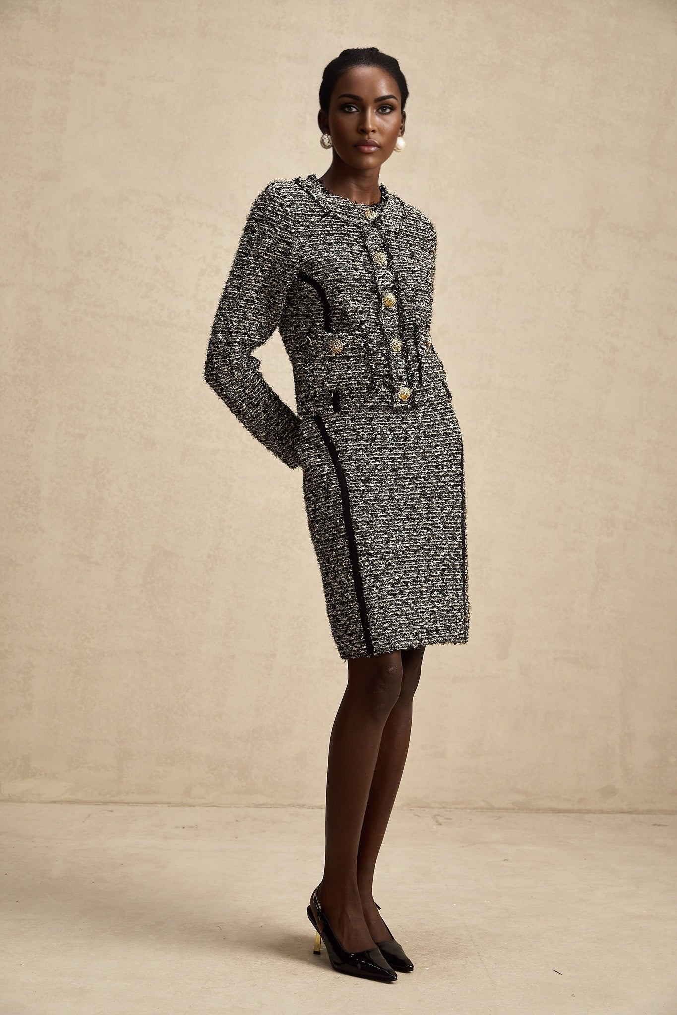 A woman wearing a matching jacket and skirt set in contrasting colors with shimmering lurex fabric details
