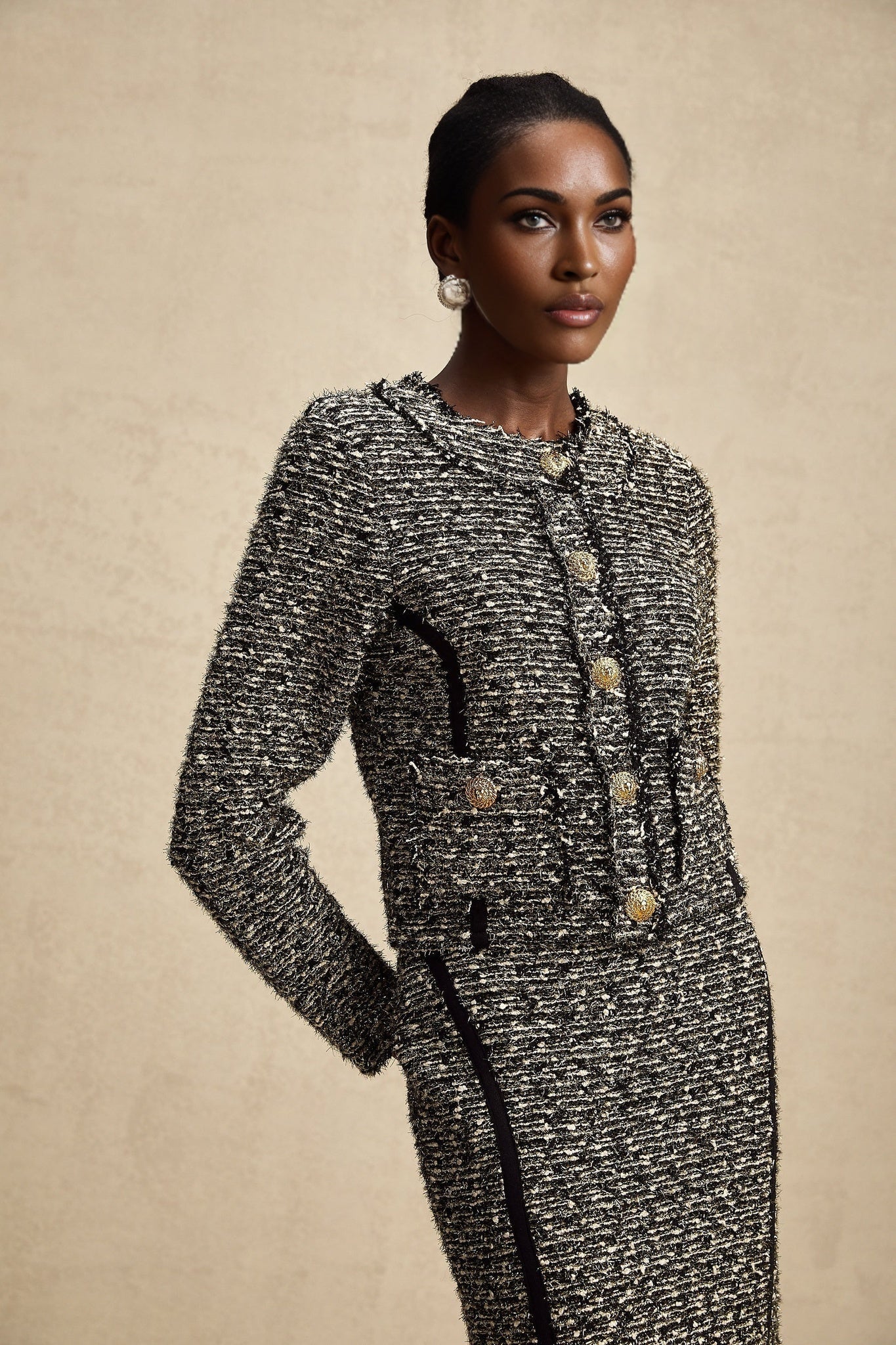 A woman wearing a matching jacket and skirt set with contrasting colors and shimmering lurex fabric