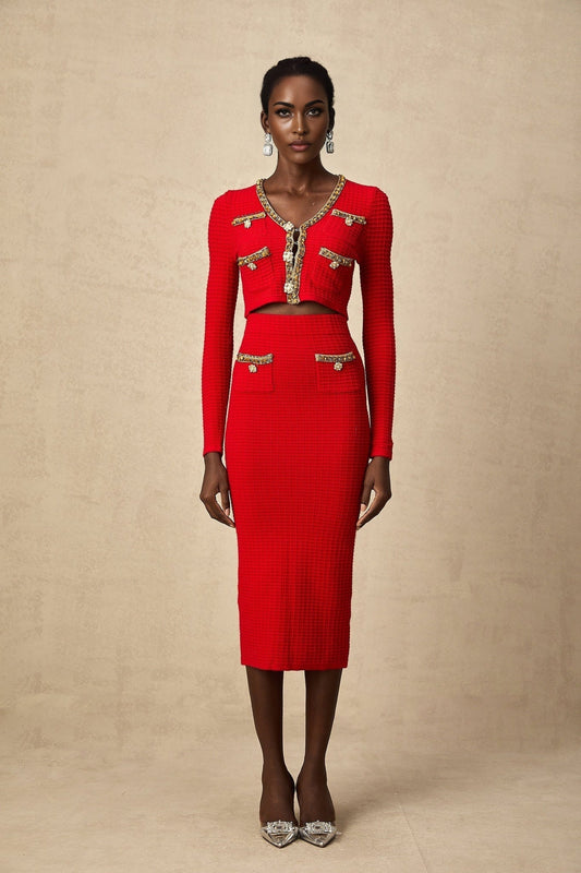 A woman wearing a matching red knitted cardigan and skirt set The cardigan features embellishments and both pieces have a textured knit pattern The outfit is styled on a model against a plain background