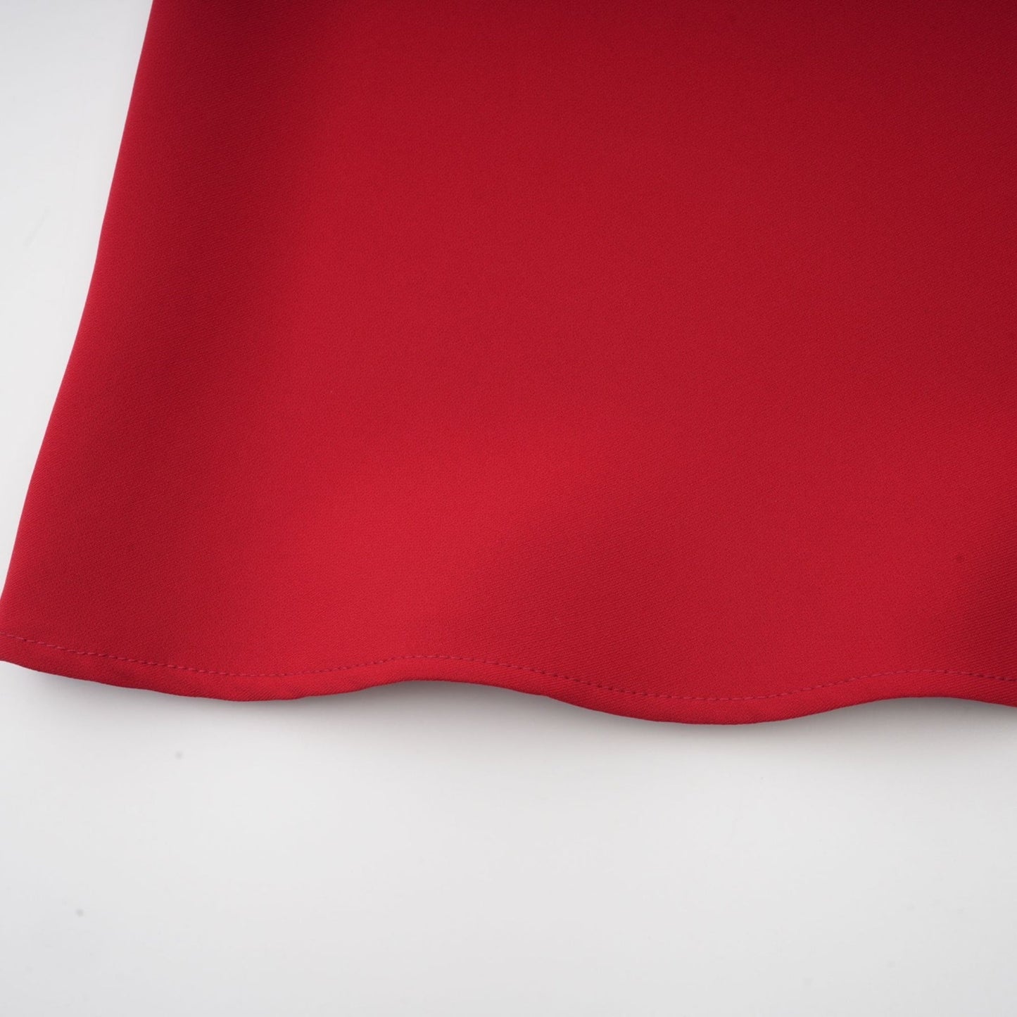 A woman wearing a matching red outfit consisting of a pleated blouse and skirt The blouse has a loose fit with long sleeves while the skirt falls to mid thigh Both pieces feature pleated detailing for a coordinated look