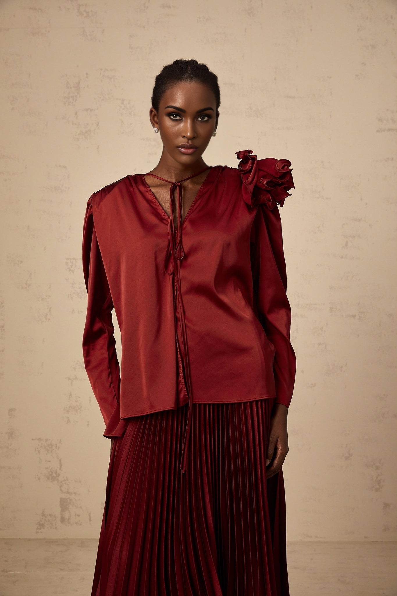 A woman wearing a matching satin blouse and skirt set in light color with floral appliques on both pieces