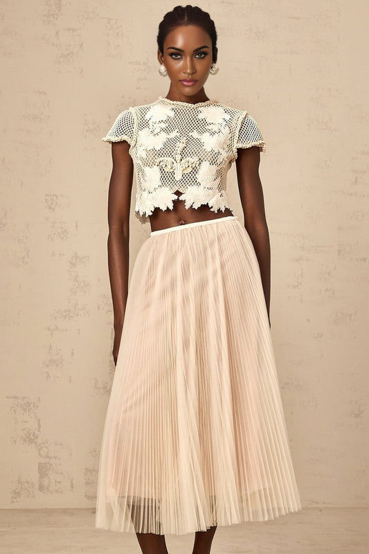A woman wearing a matching twopiece outfit consisting of a top and skirt in neutral colors with floral applique details