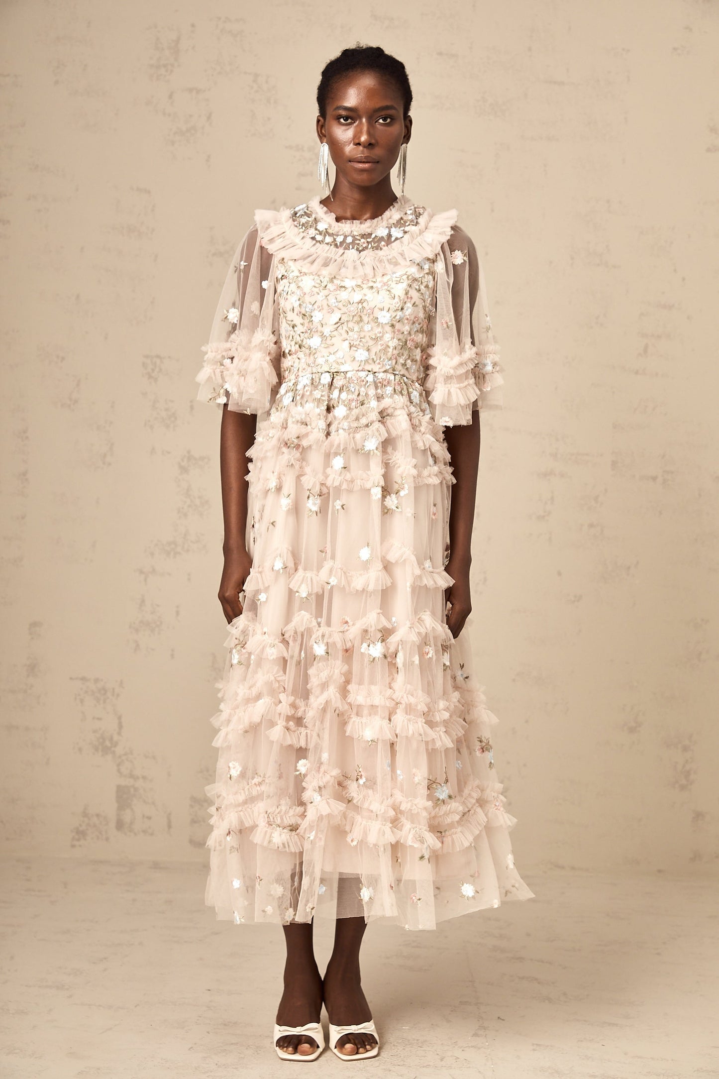 A woman wearing a midi dress with floral embroidery and tiered ruffles