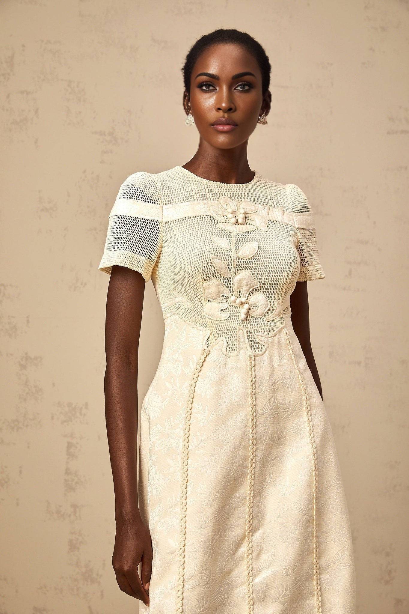 A woman wearing a midi length dress with floral embroidery and openwork details