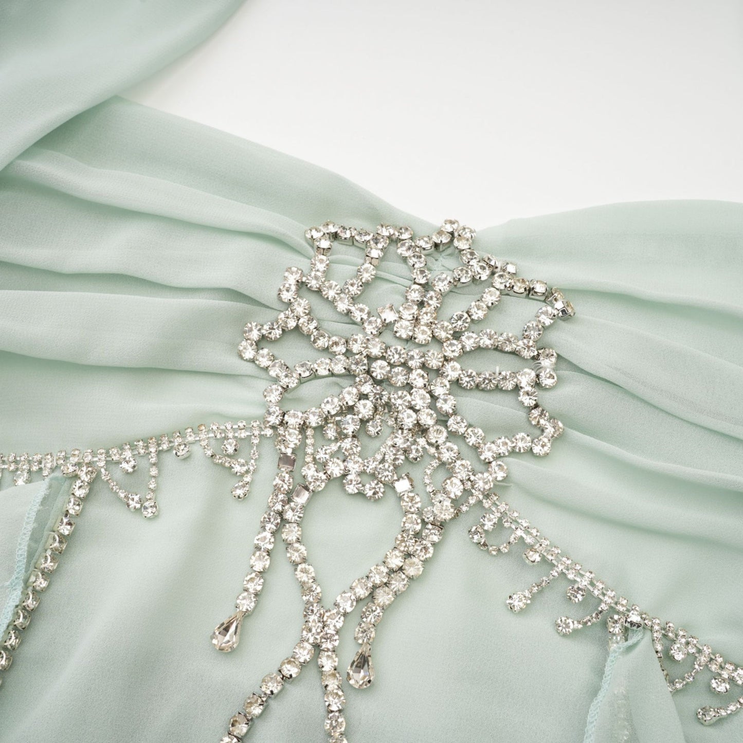 A woman wearing a midi length dress with ruffled details and embellishments named Salilah The dress features a fitted bodice and flowy skirt