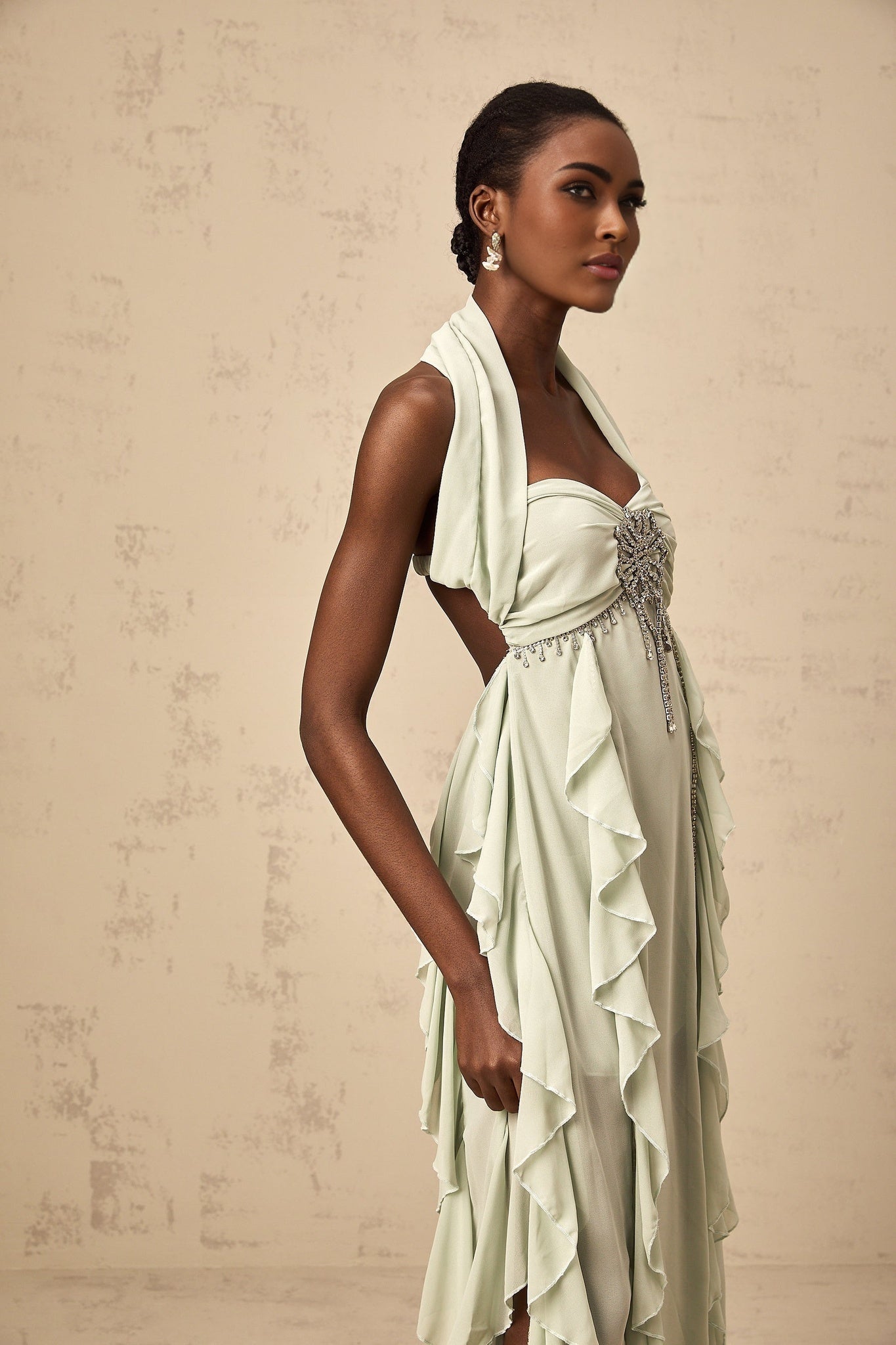 A woman wearing a midi length dress with ruffled details and embellishments standing in a neutral pose