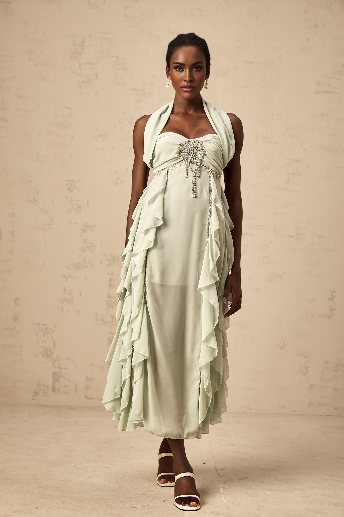 A woman wearing a midi length dress with ruffled details and embellishments The dress appears to be from the Salilah brand and has a flowy silhouette