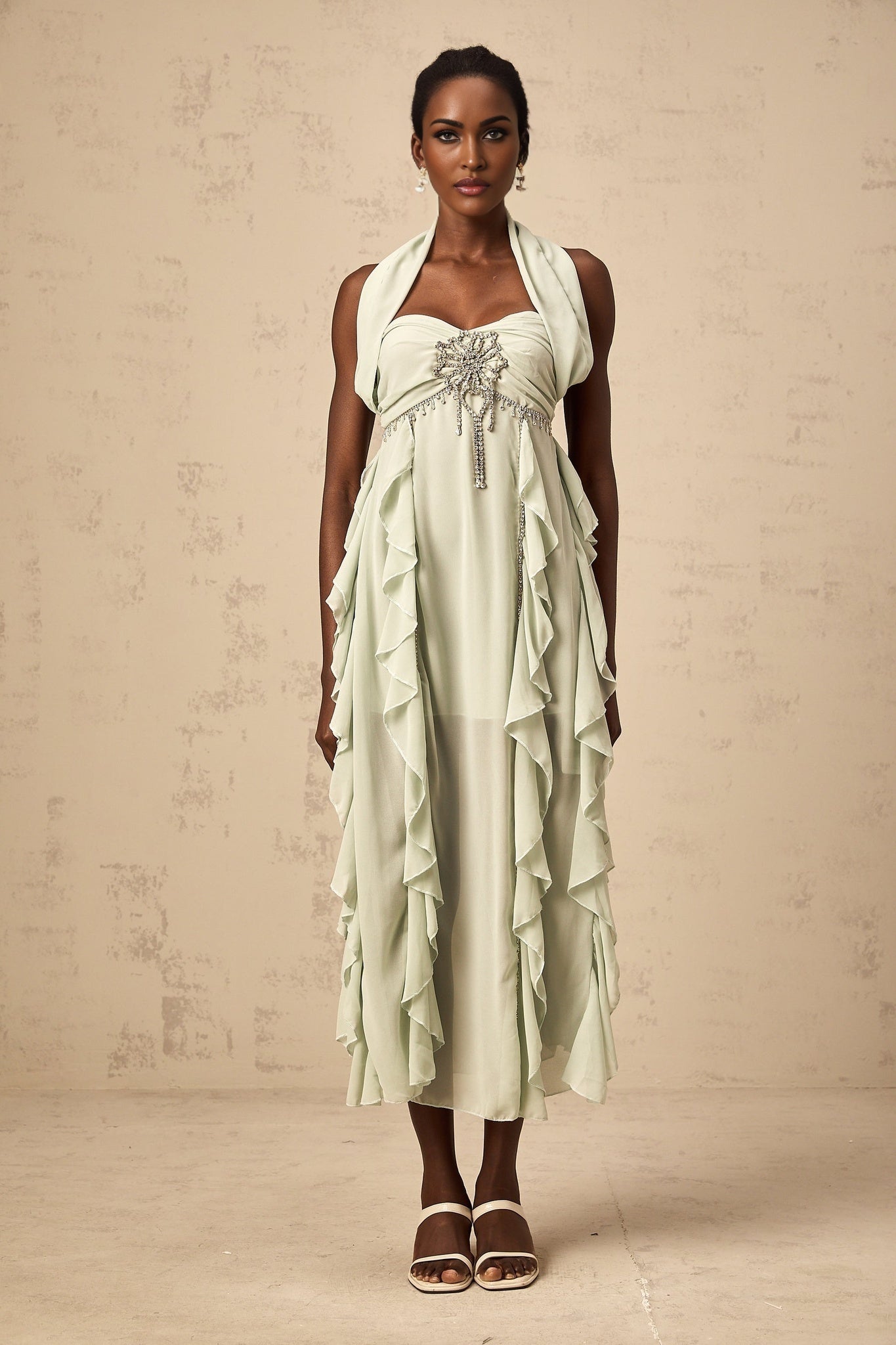 A woman wearing a midilength dress with ruffled details and embellishments named Salilah