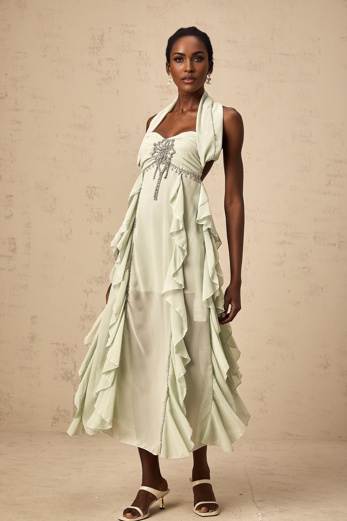 A woman wearing a midilength dress with ruffled details and embellishments named Salilah