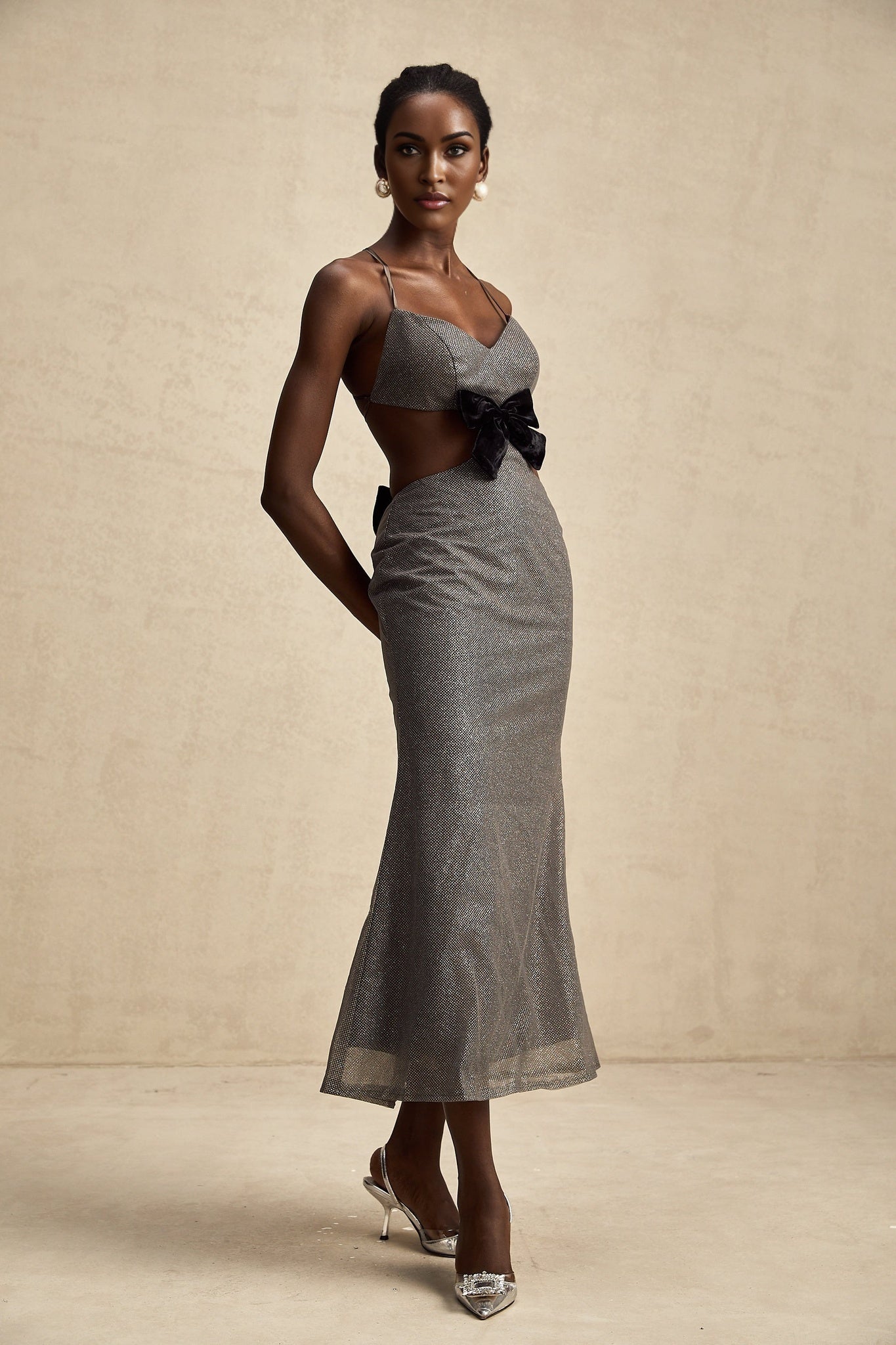 A woman wearing a midlength dress with an open back and sequin details named Violaine