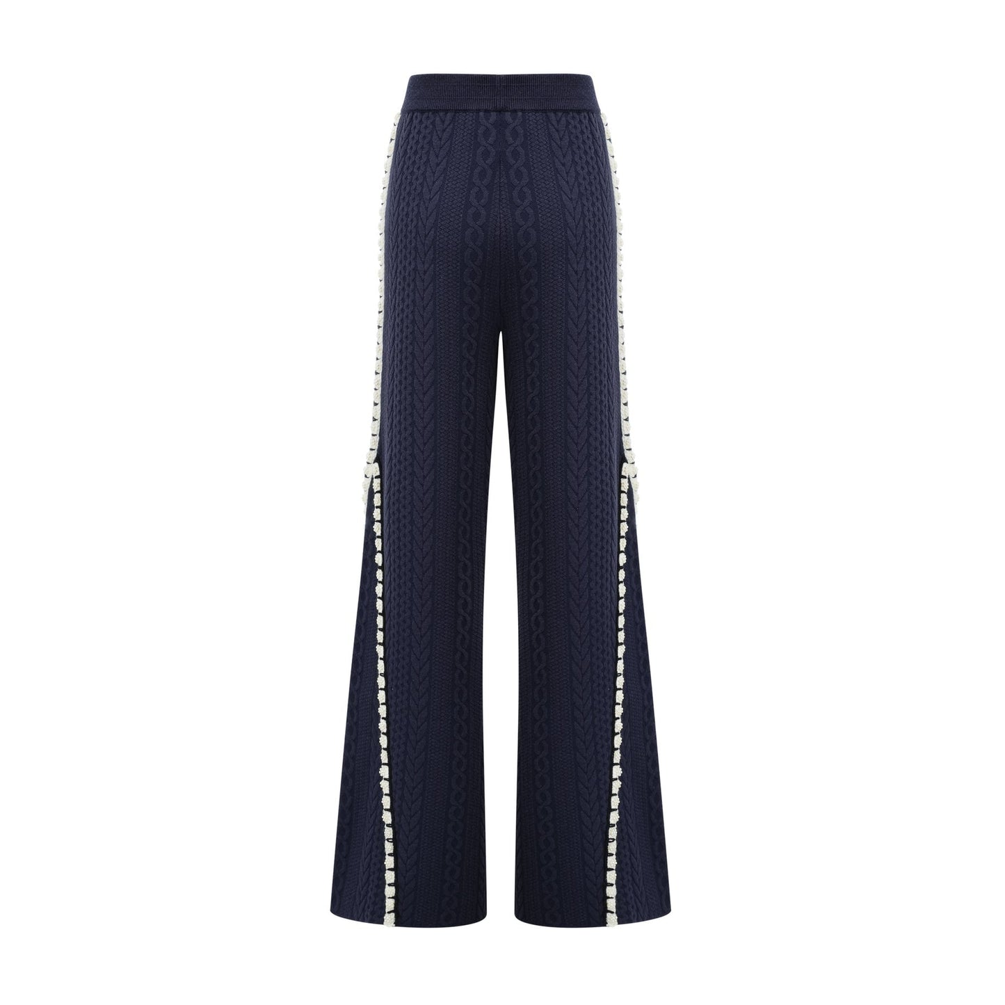 A woman wearing a navy blue crochet knit cardigan and matching trousers standing against a plain background