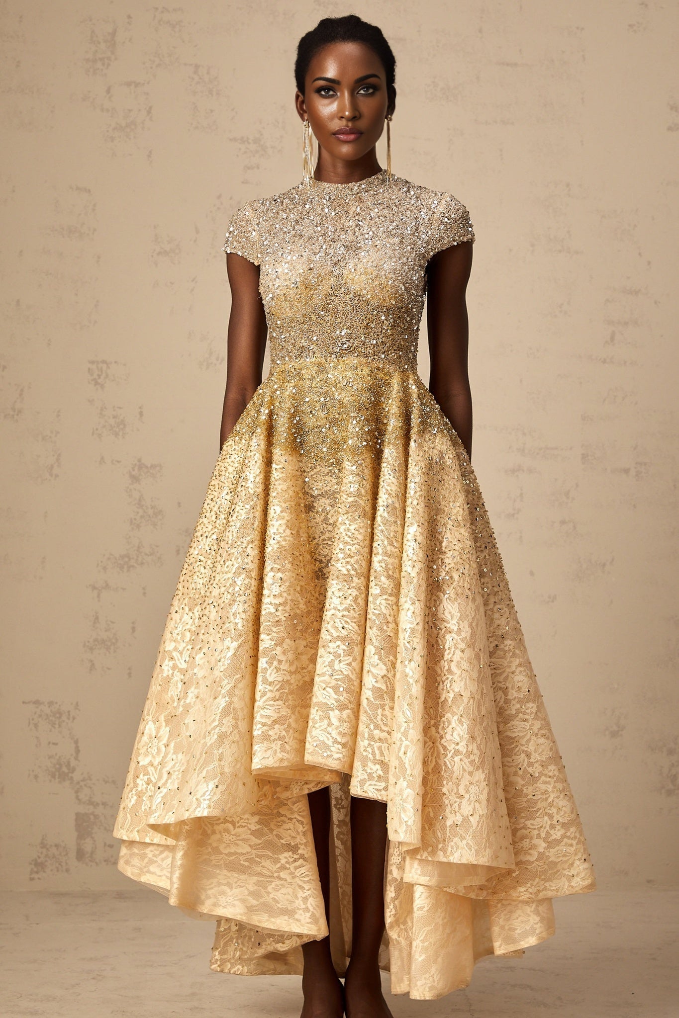A woman wearing a neutral colored sequined dress with a high low hemline