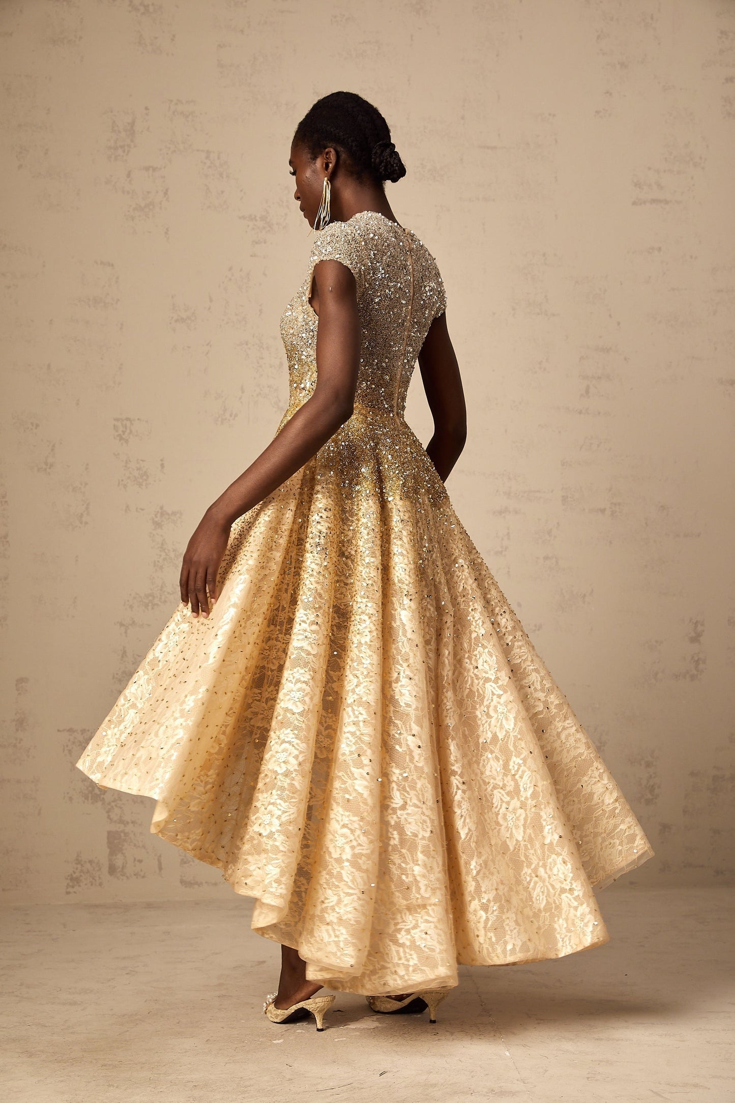 A woman wearing a neutral colored sequined dress with a high low hemline