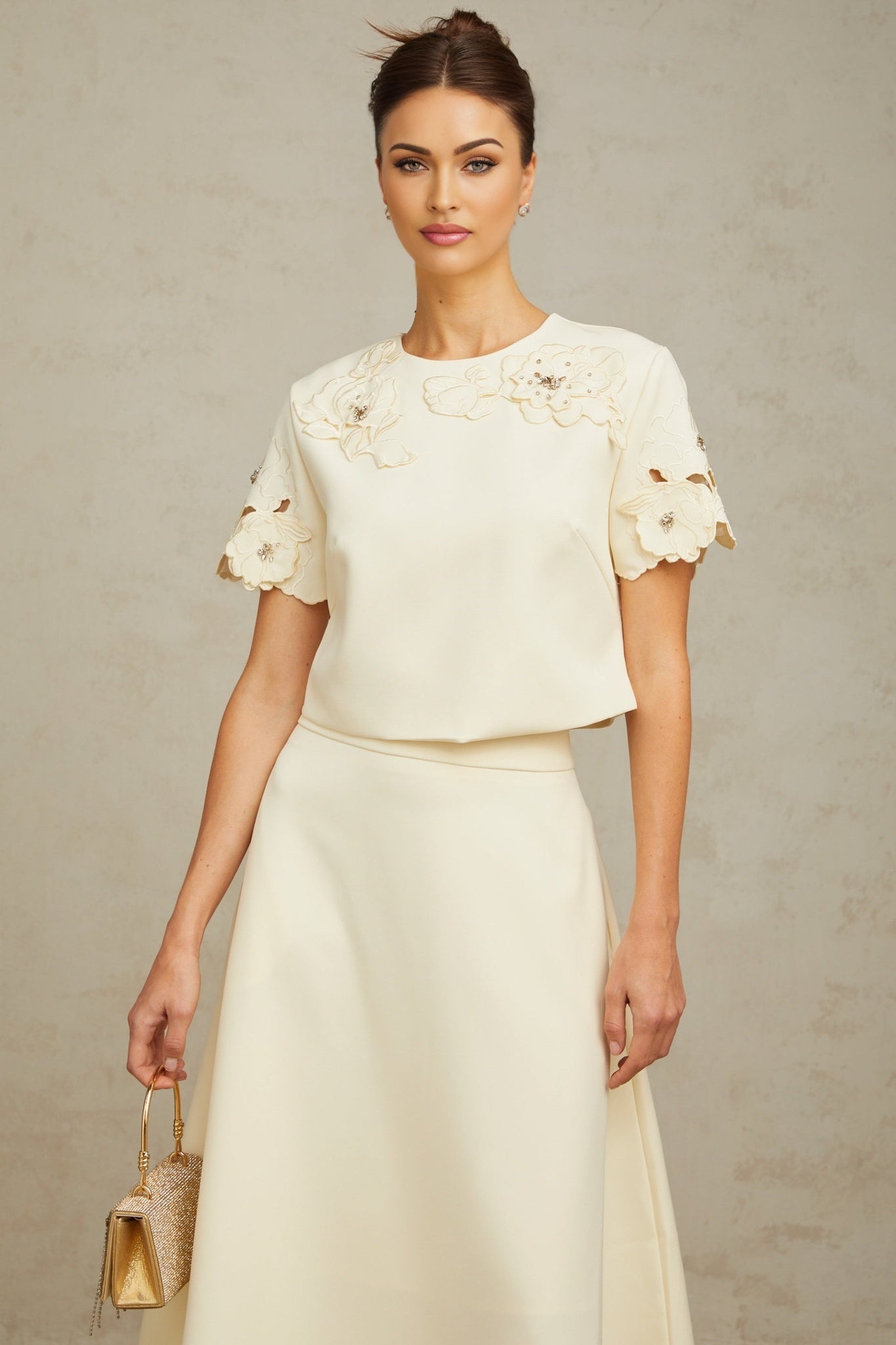 A woman wearing a neutralcolored matching set consisting of a top and skirt The top features delicate 3D petal details and the skirt has a fitted silhouette Both pieces are in soft beige tones creating an elegant and feminine ensemble