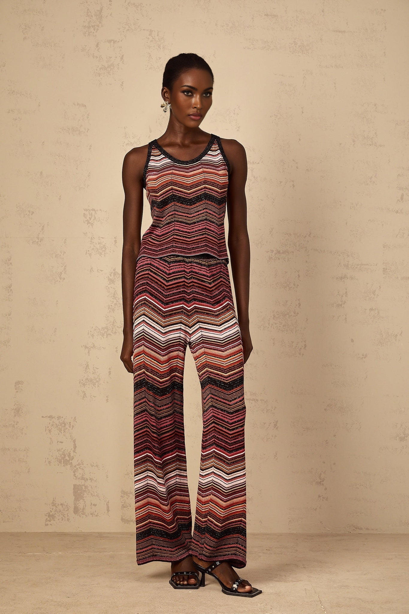A woman wearing a red and white striped knit matching set consisting of a top and pants from Chloe