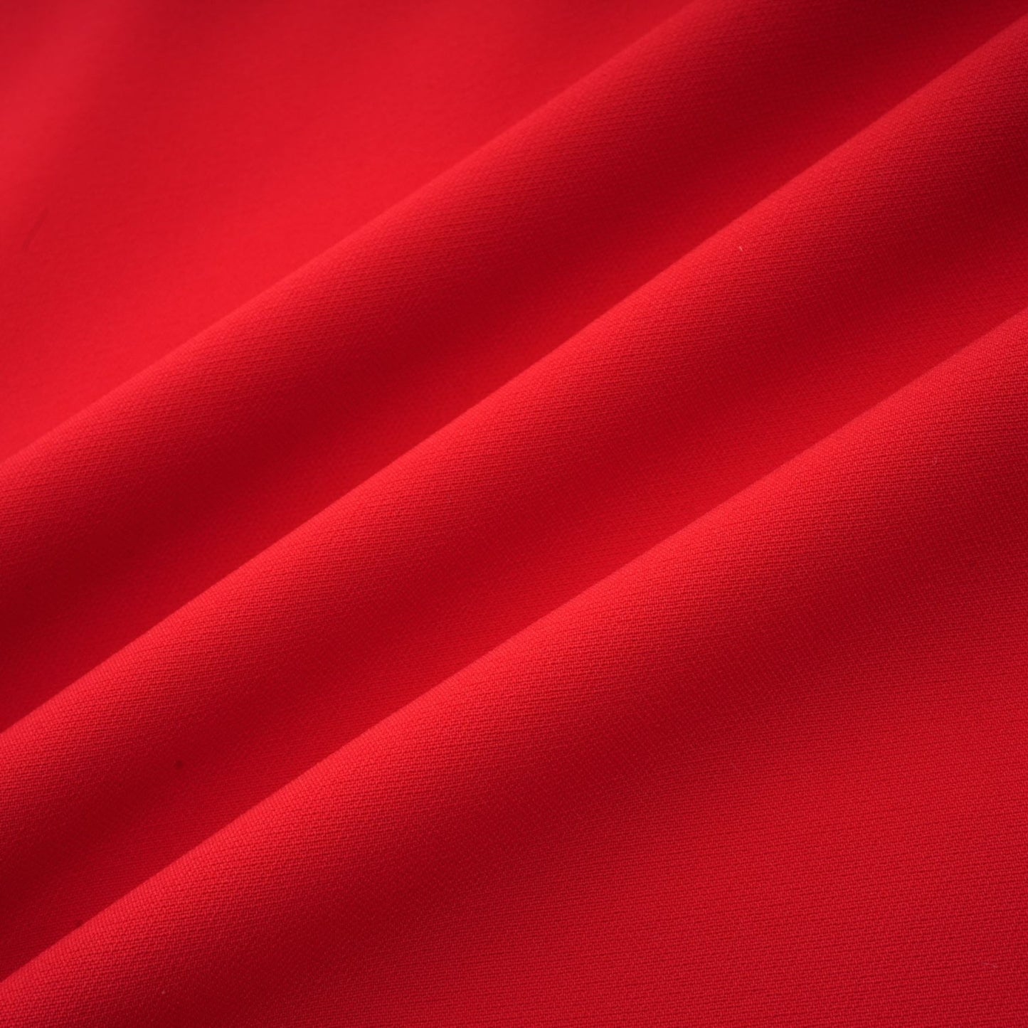 A woman wearing a red long sleeve dress with a floral pattern standing against a plain background