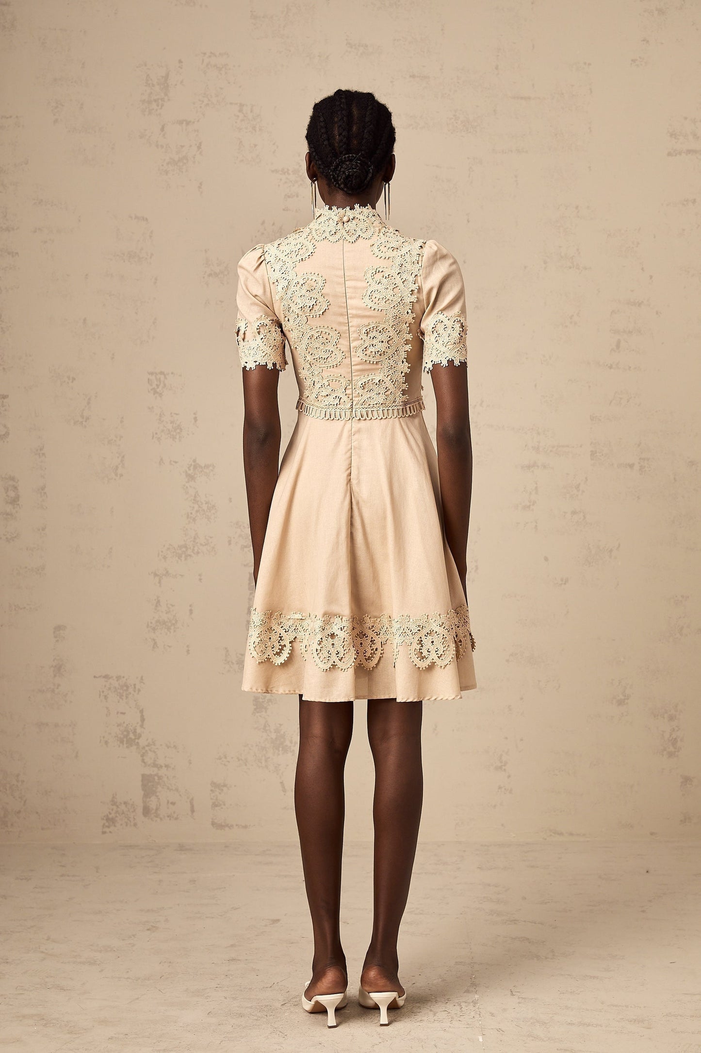 A woman wearing a short flared dress with corded lace detailing and a feminine silhouette