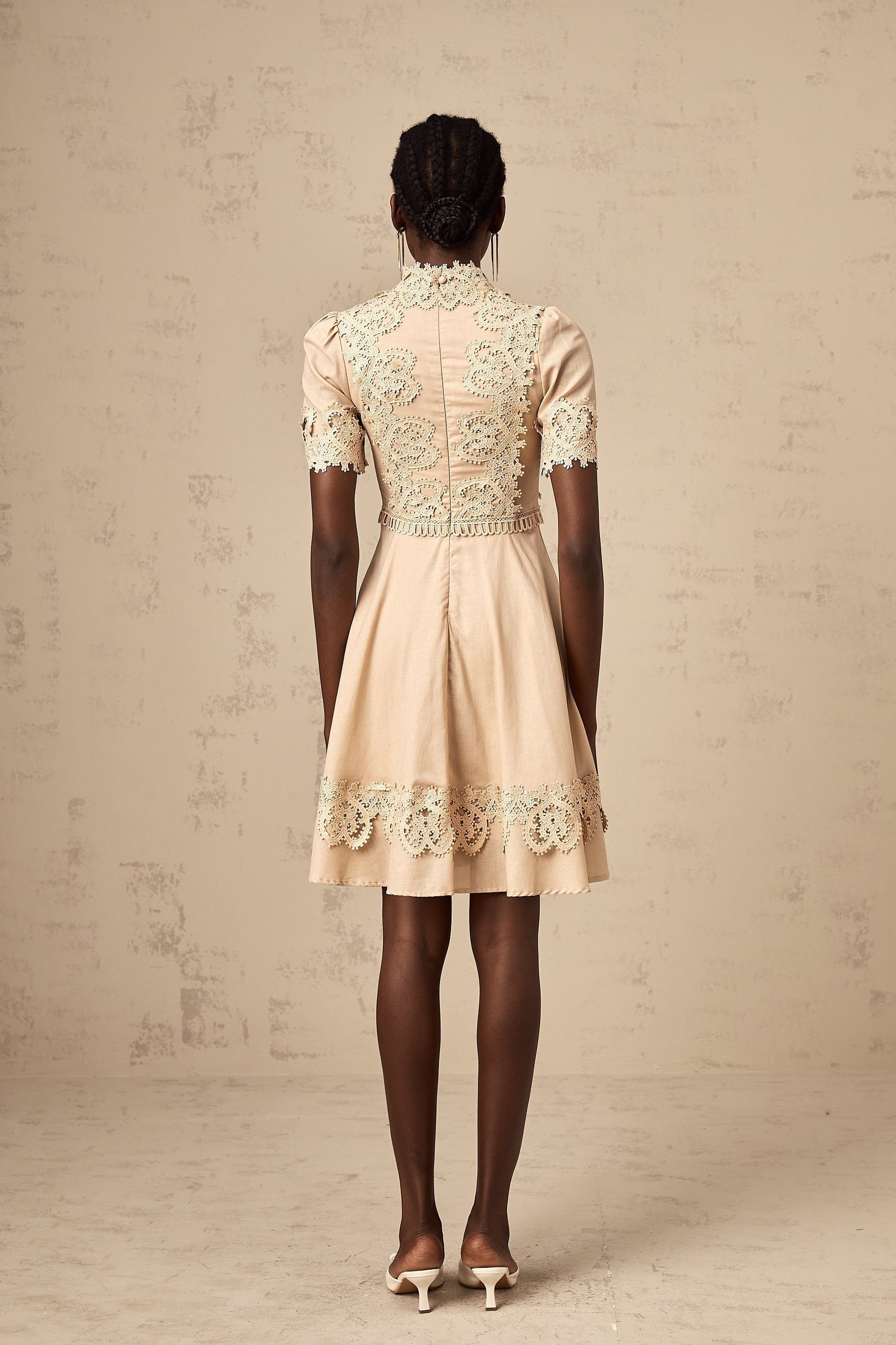 A woman wearing a short flared dress with corded lace detailing and a feminine silhouette