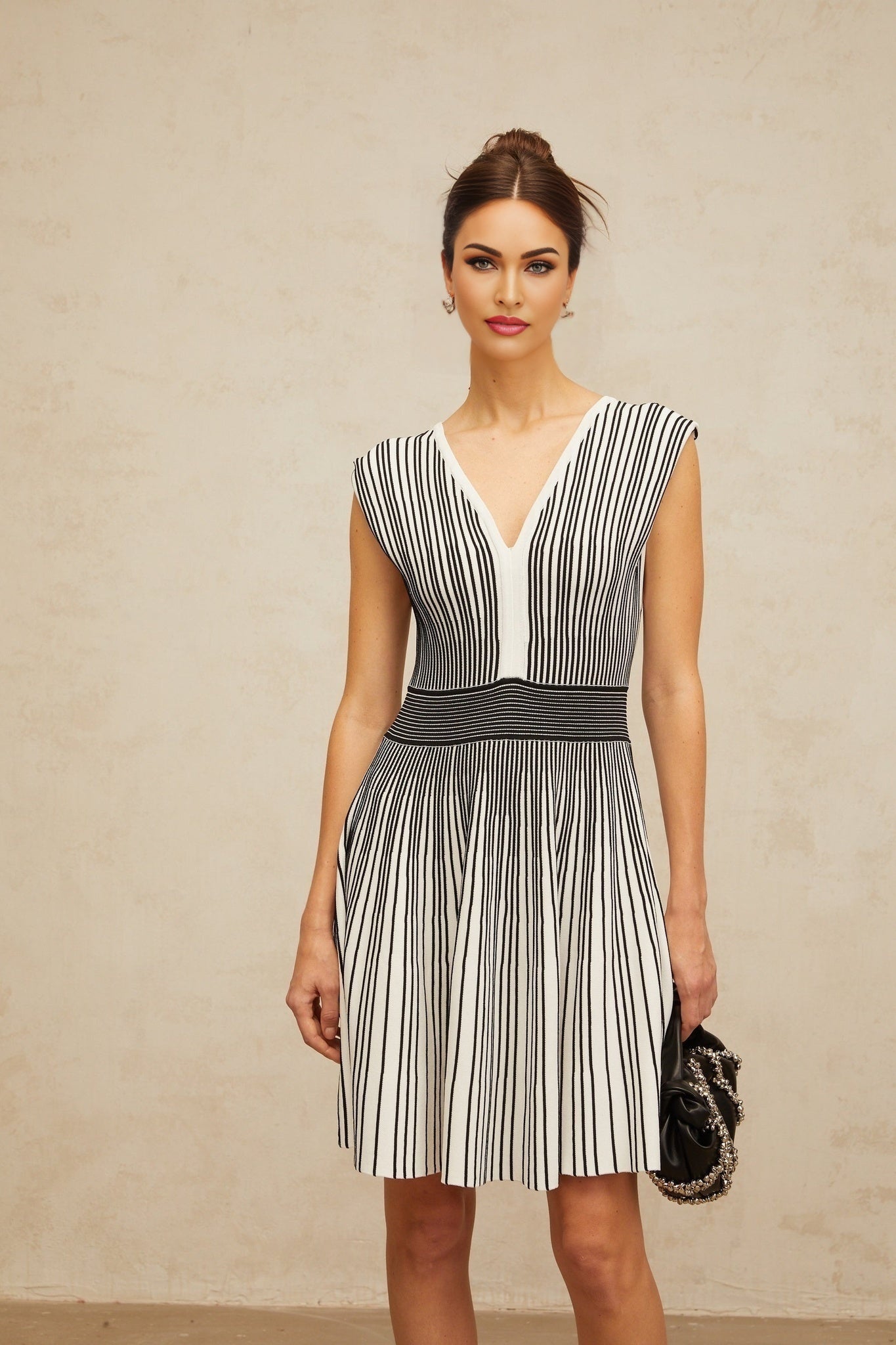 A woman wearing a short knitted dress with vertical stripes in contrasting colors