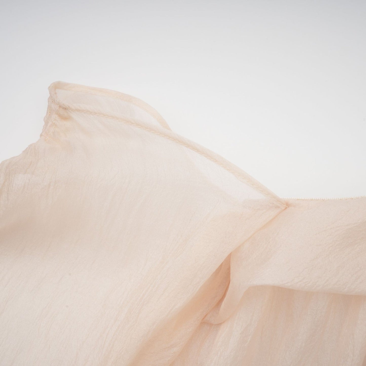 A woman wearing a short offshoulder dress with ruched detailing and layered fabric The dress has selftie straps and falls above the knee The model is posing to showcase the dress design