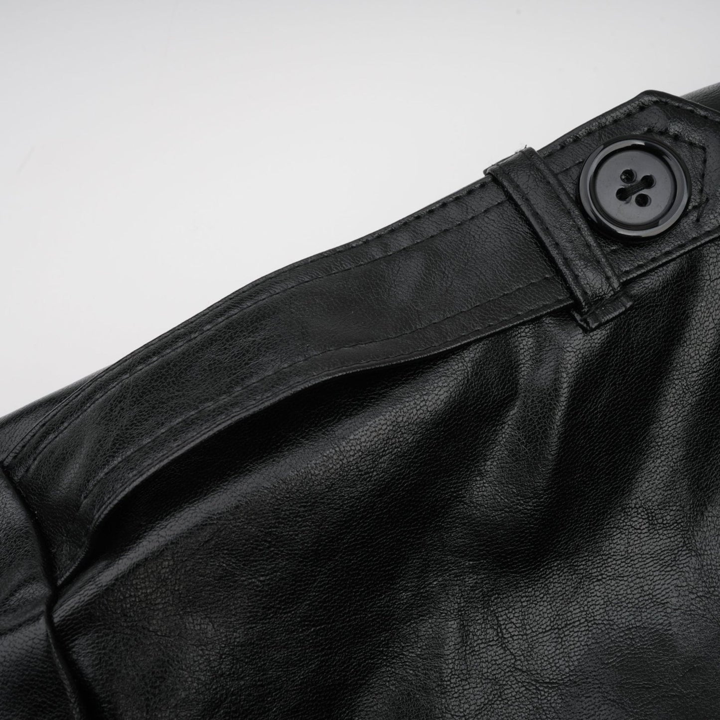 A woman wearing a short quilted leather jacket in a dark color standing against a plain background