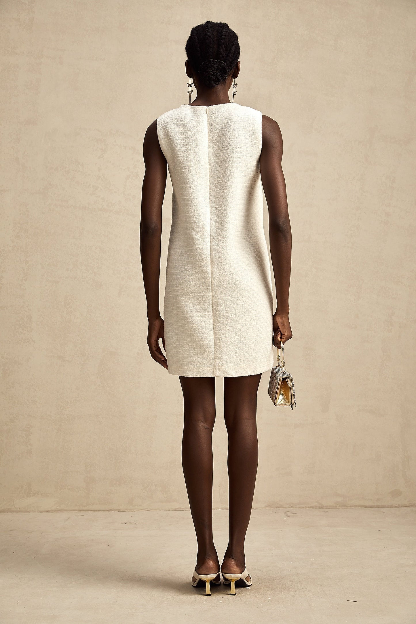 A woman wearing a short tweed dress with embroidery details and cutout sections
