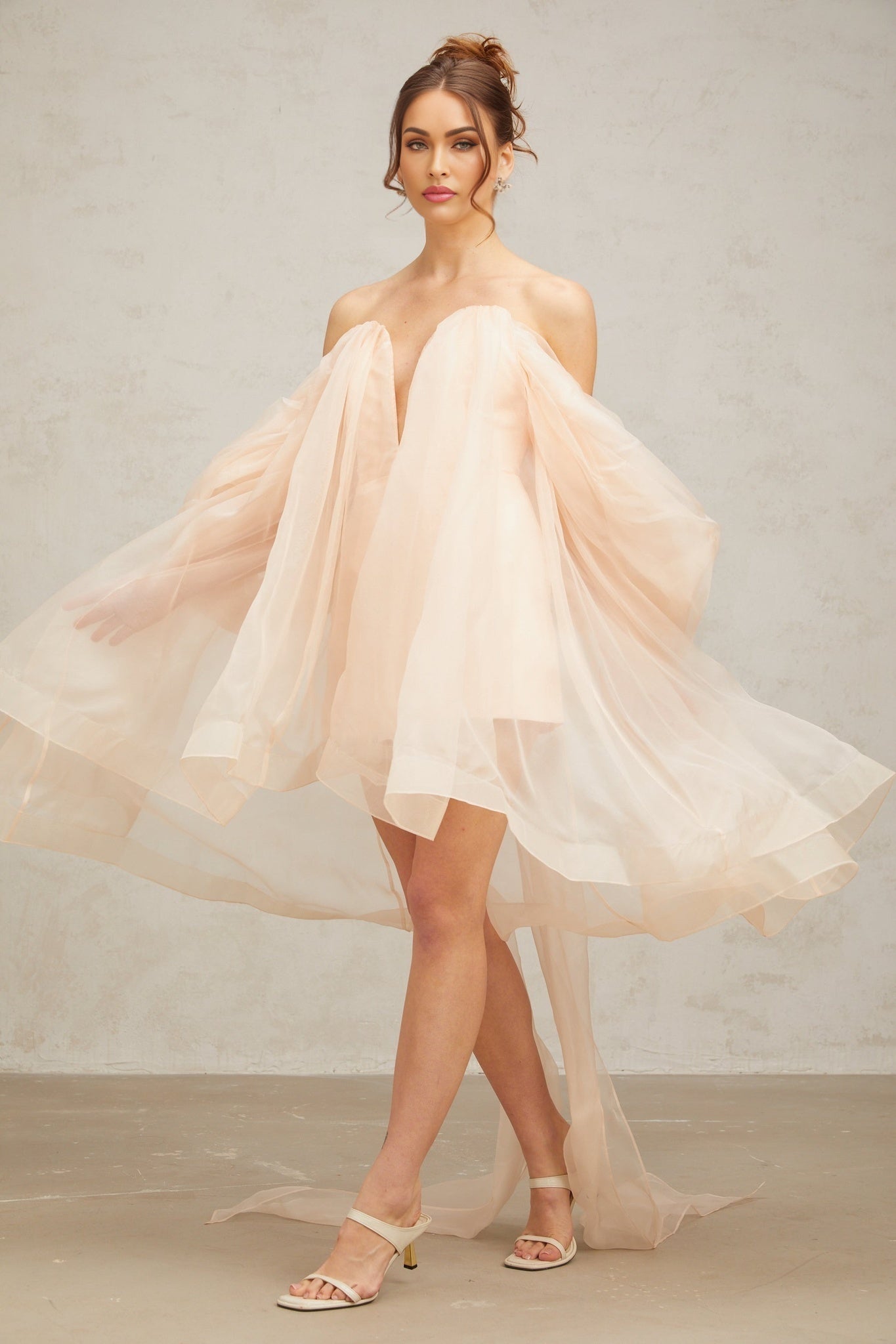 A woman wearing a short voluminous mini dress with a large bow detail at the neckline