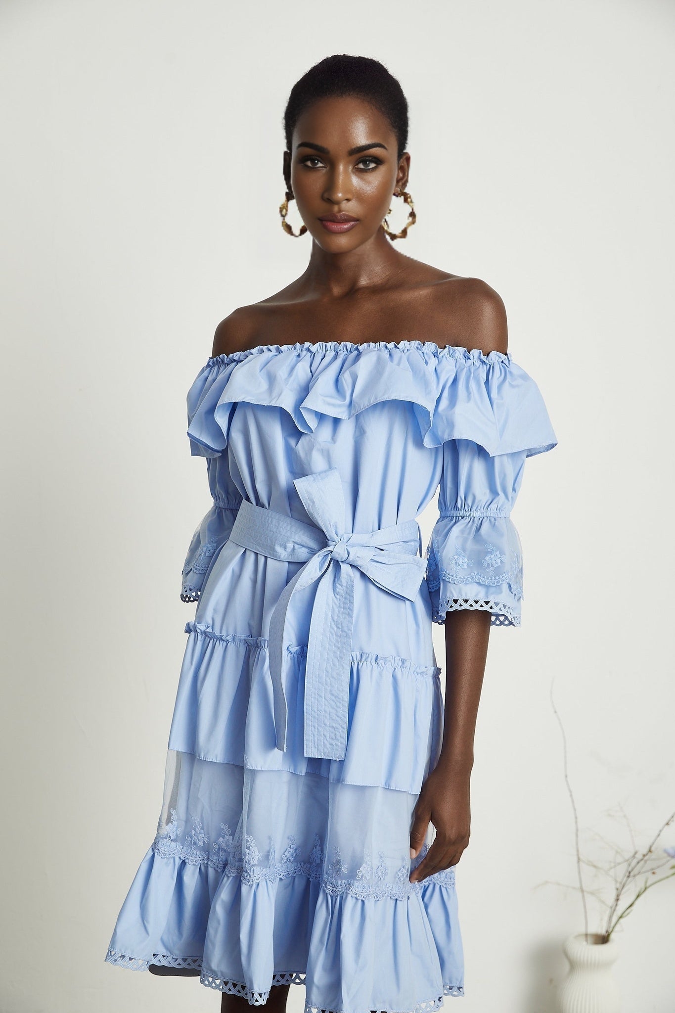 A woman wearing a shoulderoff tiered midi dress named Sophie in a soft flowing fabric