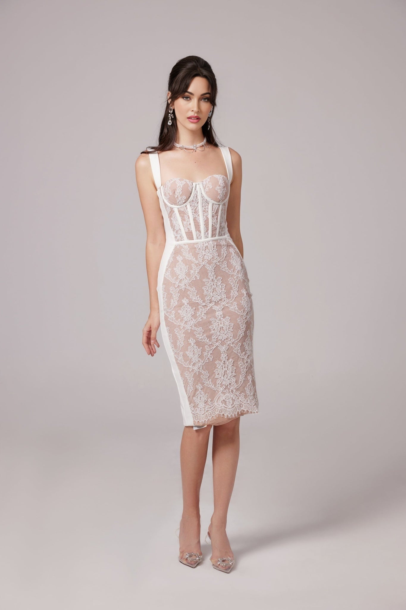 A woman wearing a strapless beige midi dress with a bandage style fabric and bustierlike top