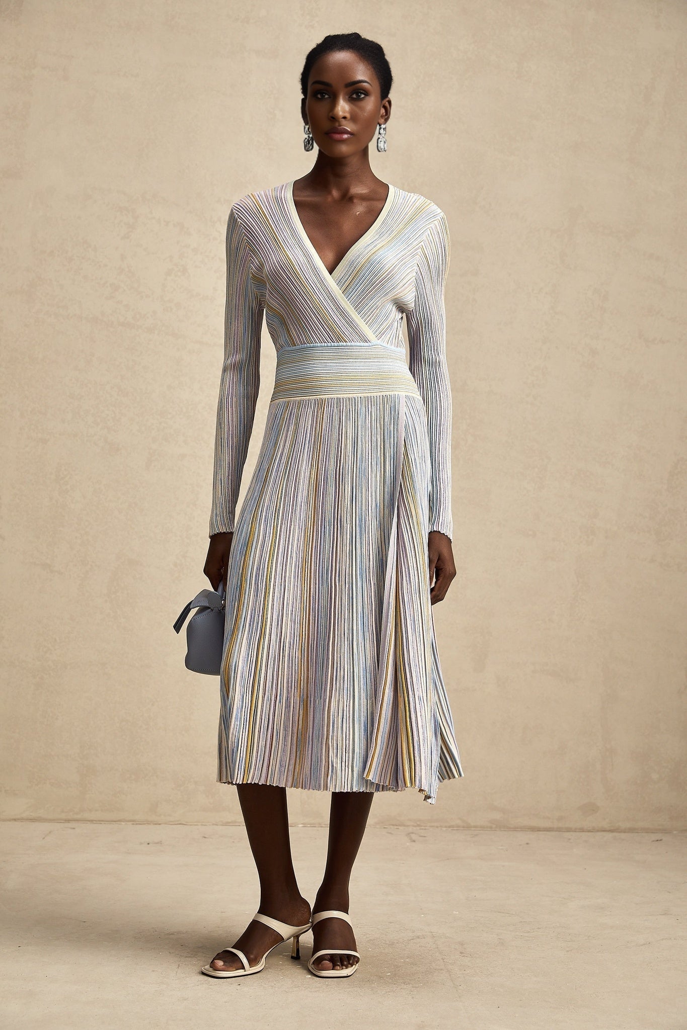 A woman wearing a vertical striped knitted midi dress with long sleeves and a fitted silhouette The dress features alternating stripes in different colors and has a round neckline