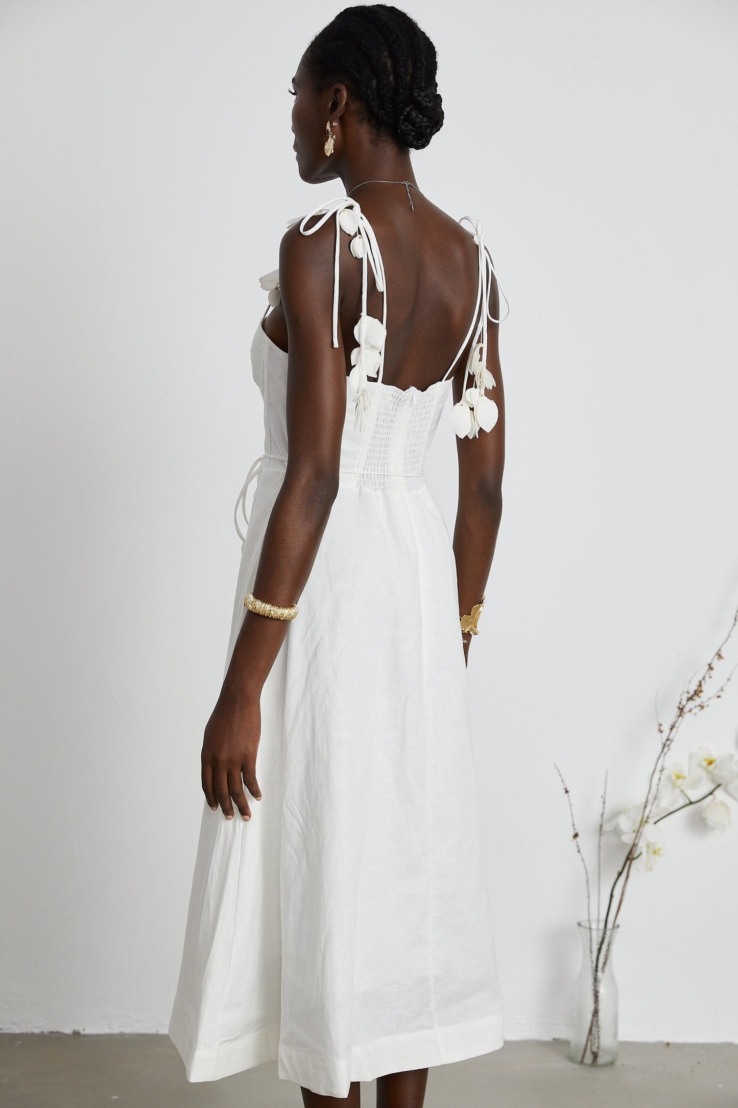A woman wearing a white corset midi dress with a fitted bodice and flared skirt standing against a plain background