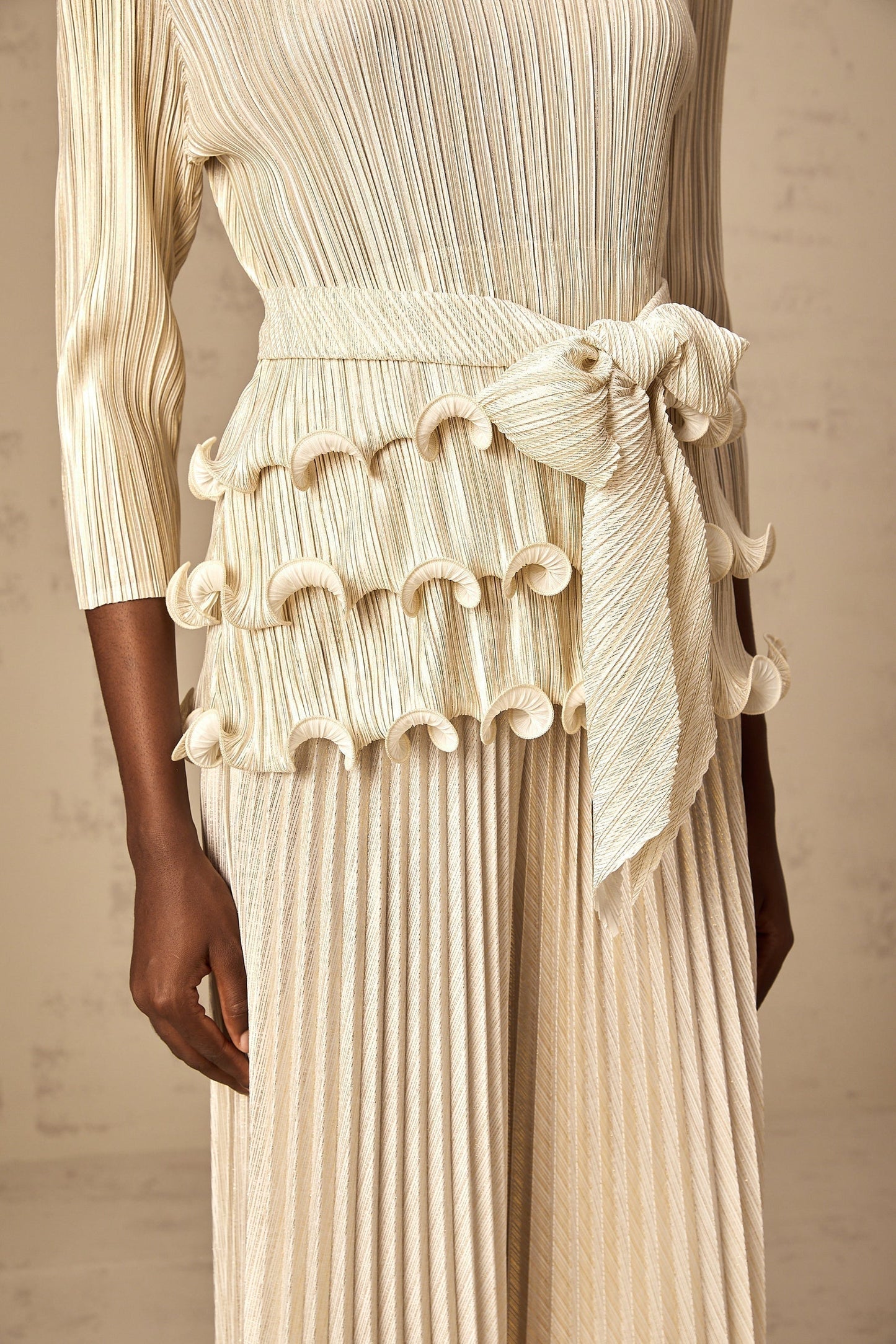 A woman wearing a white jumpsuit with floral appliques ruffles and pleated details