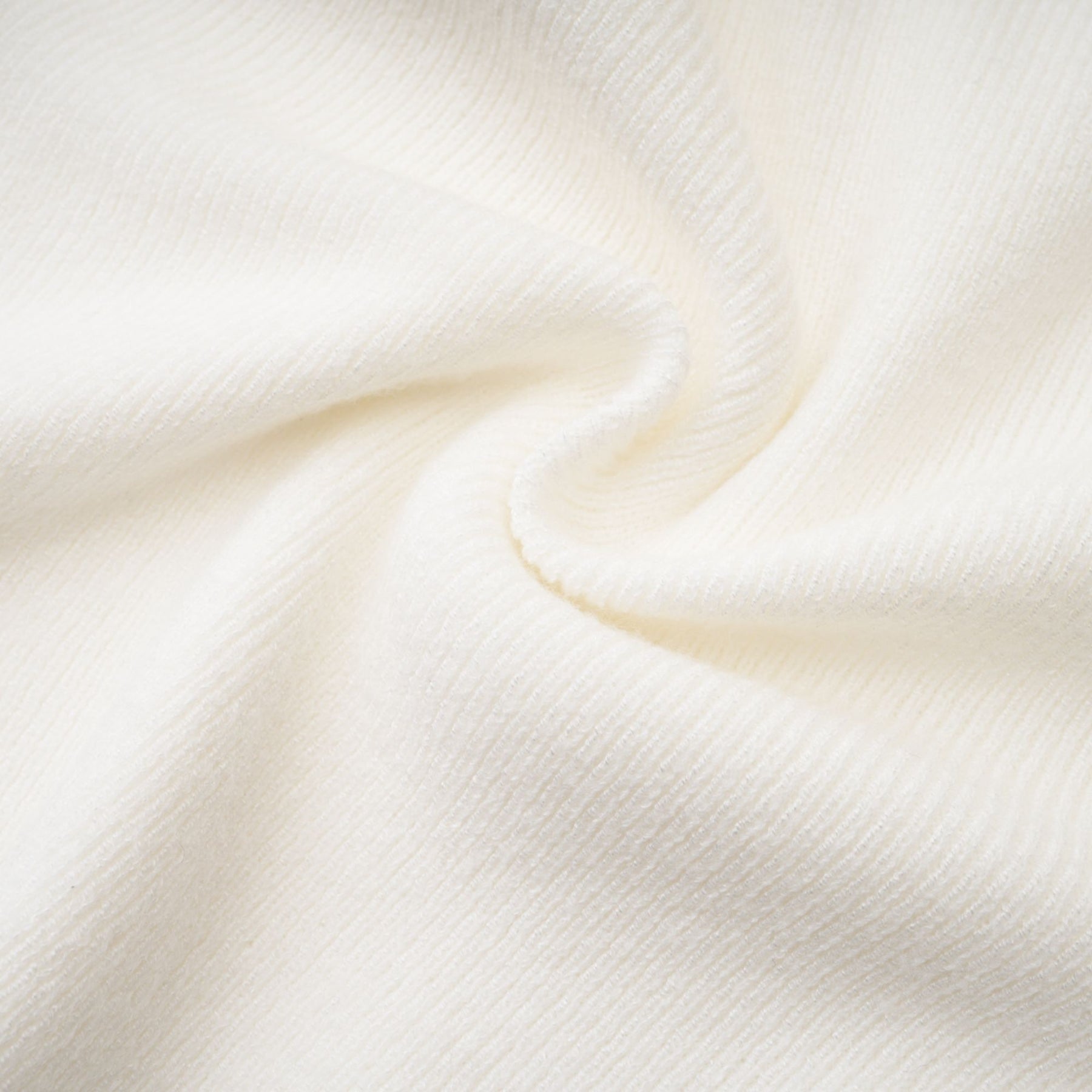 A woman wearing a white knitted strapless long sleeve top with a ribbed texture