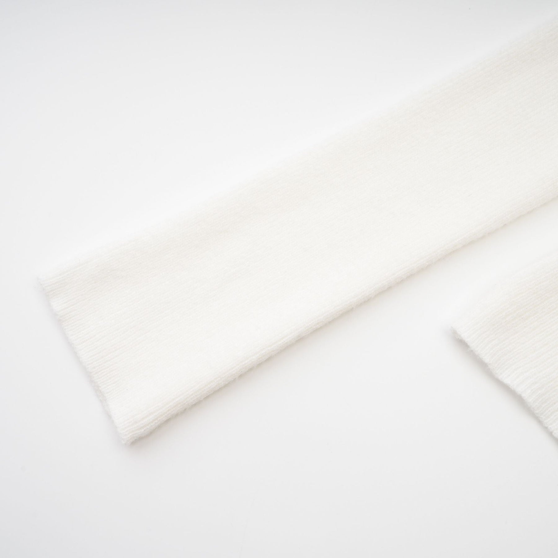 A woman wearing a white knitted strapless long sleeve top with a textured pattern and fitted design