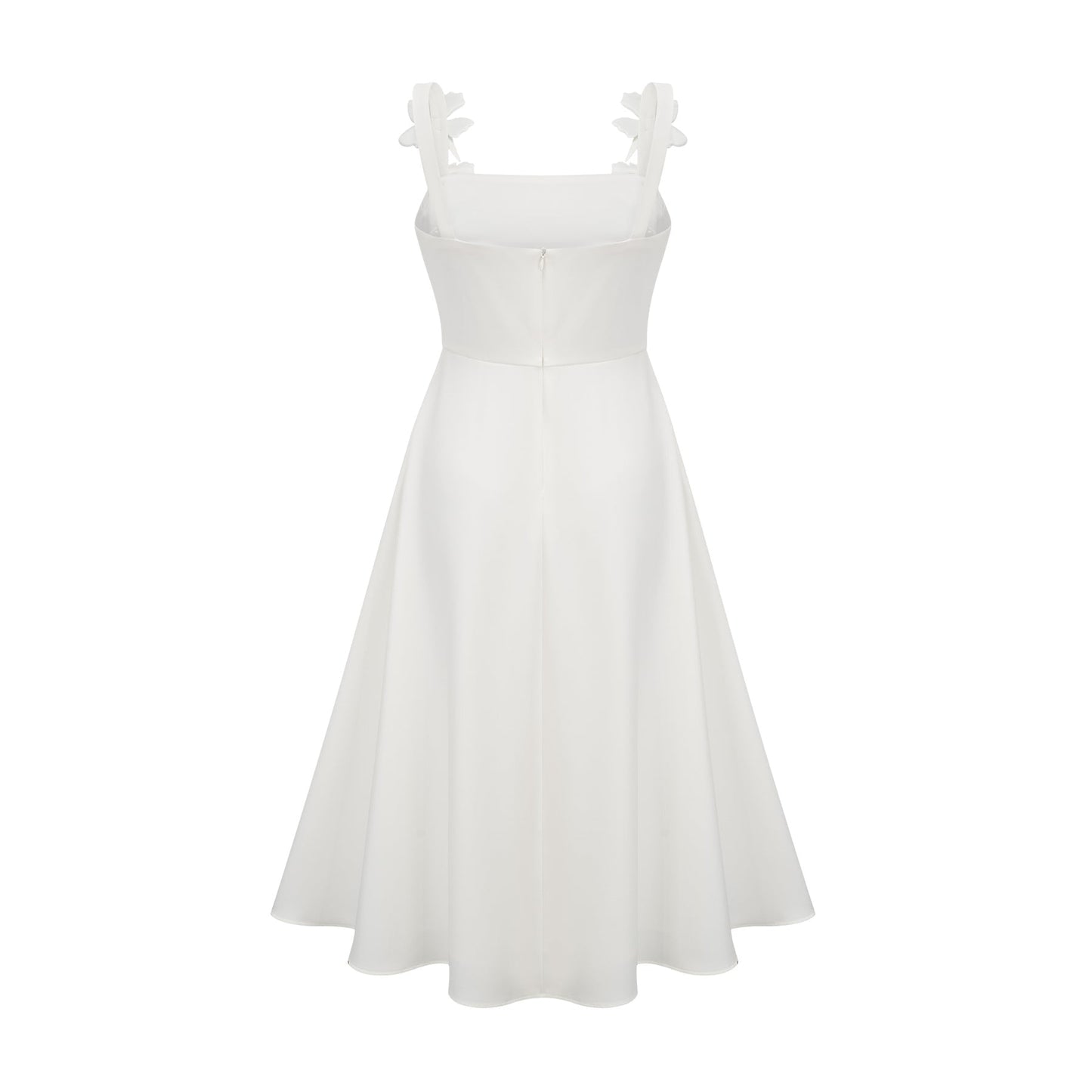 A woman wearing a white midi dress with a square neckline and faux flower embellishments standing against a plain background
