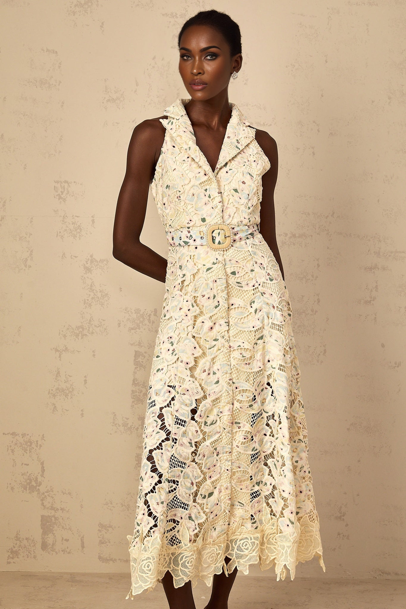 A woman wearing a white midi dress with floral embroidery and cutout details standing in a relaxed pose