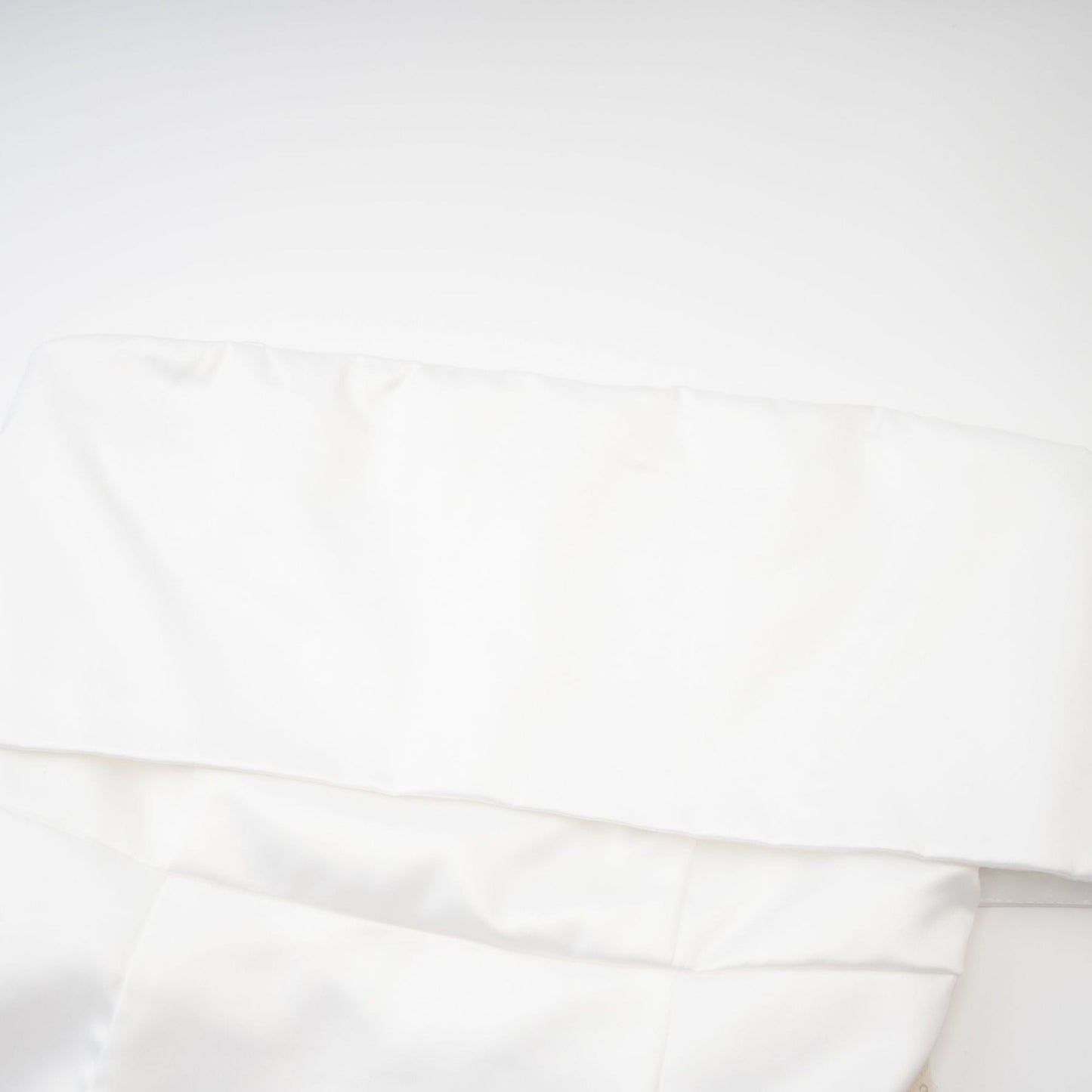 A woman wearing a white off the shoulder dress with a flowy silhouette standing against a neutral background