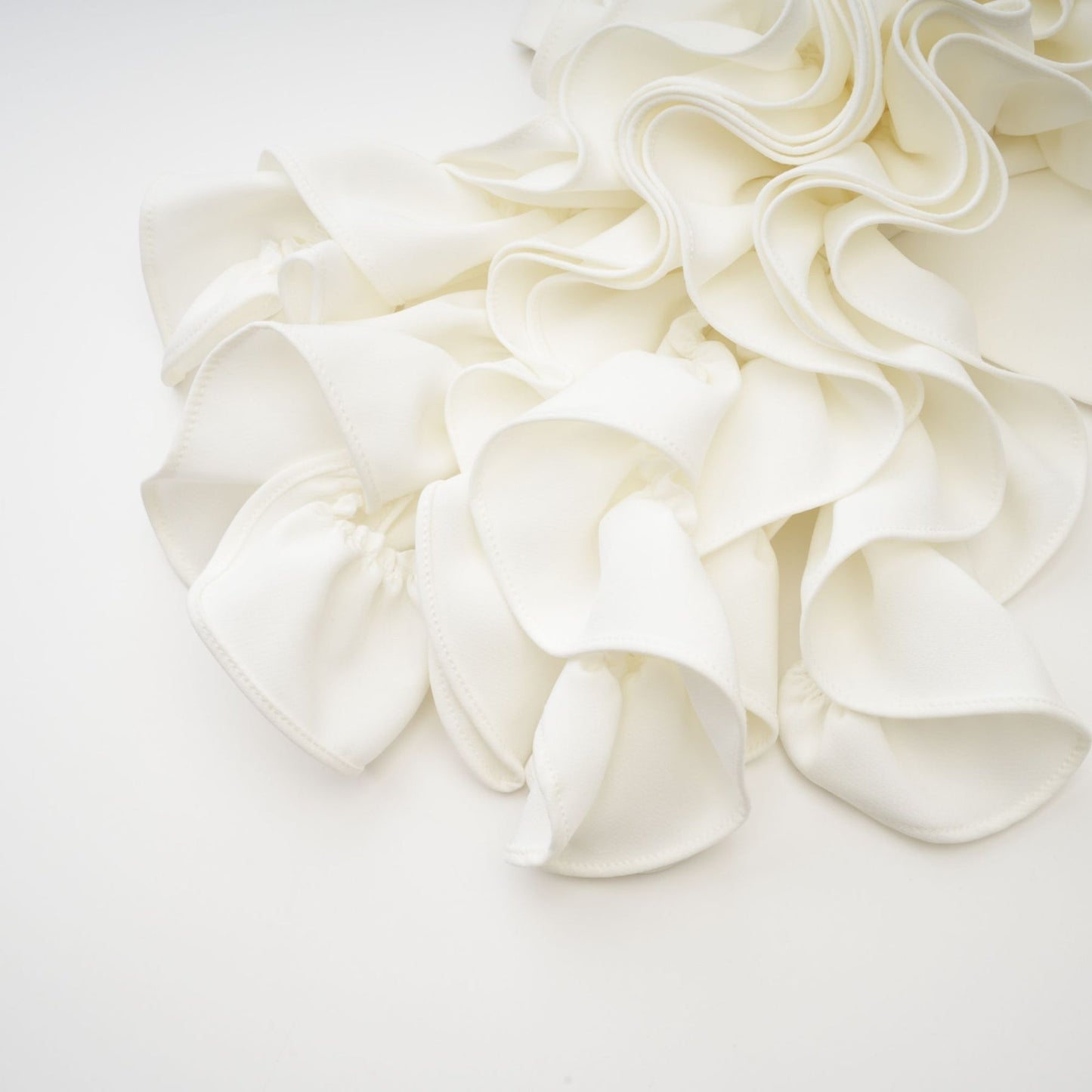 A woman wearing a white sleeveless top with delicate floral applique details on the front