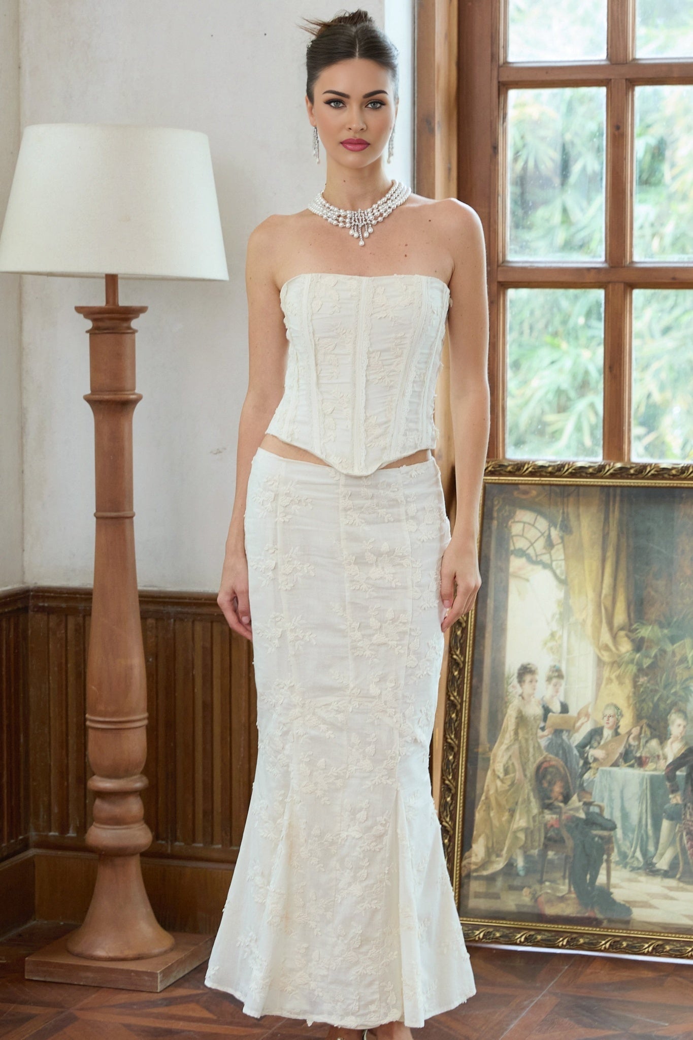 A woman wearing a white twopiece outfit consisting of an embroidered top and matching skirt set called Margot